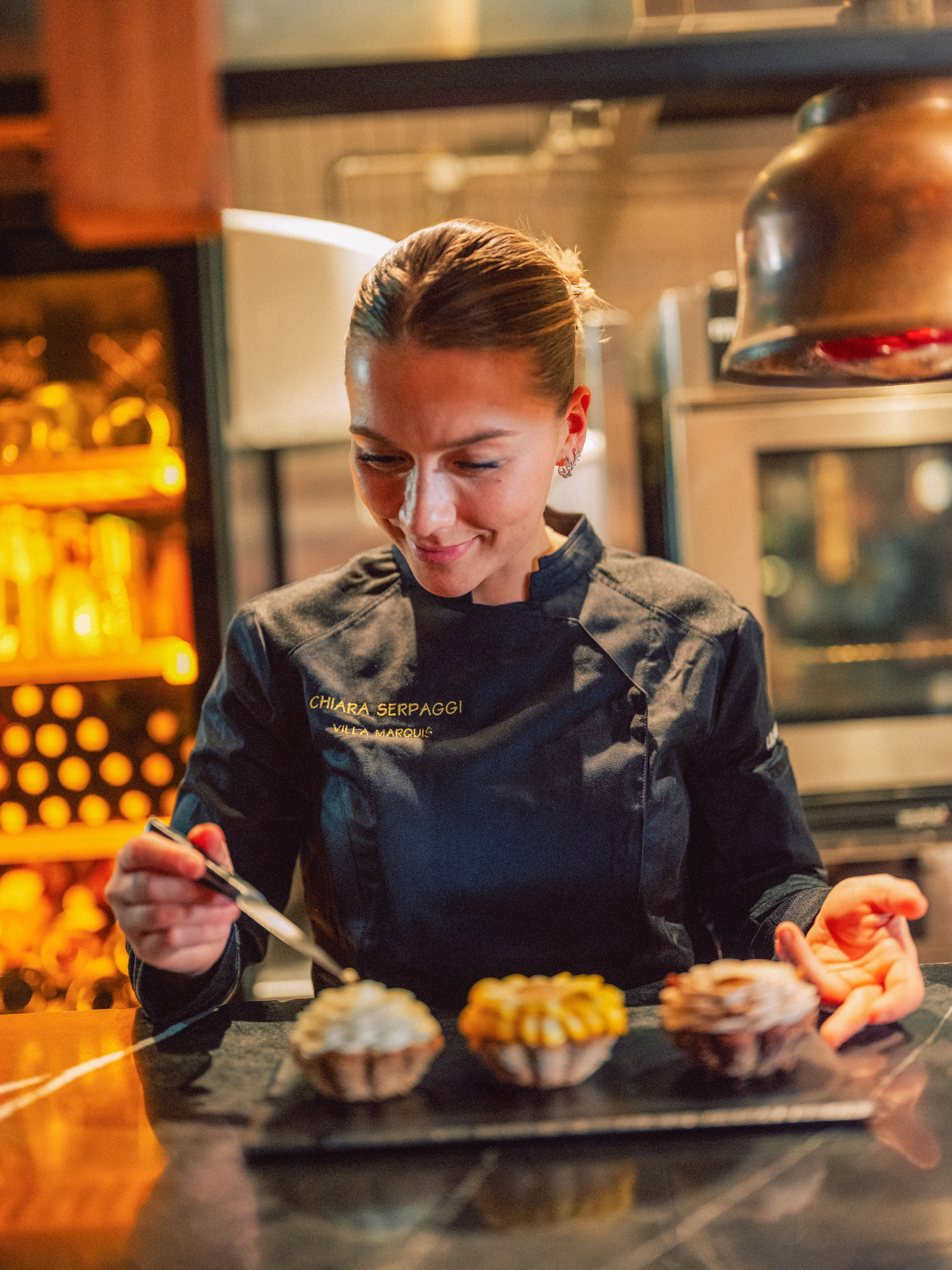 Chiara Serpaggi, Villa Marquis chef, garnishing three exquisite pastries.