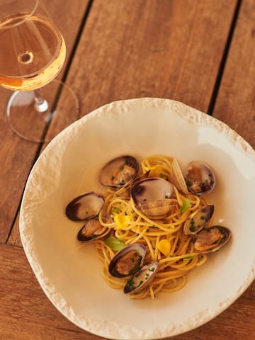 a plate of pasta with clams and a glass of wine