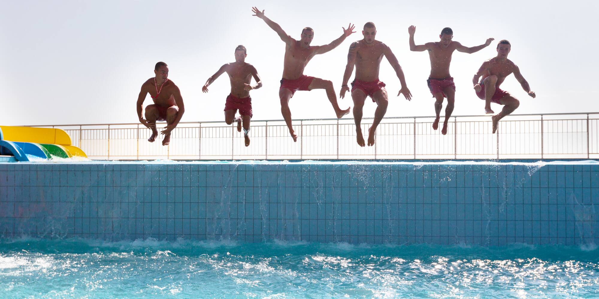 a group of men jumping into a pool