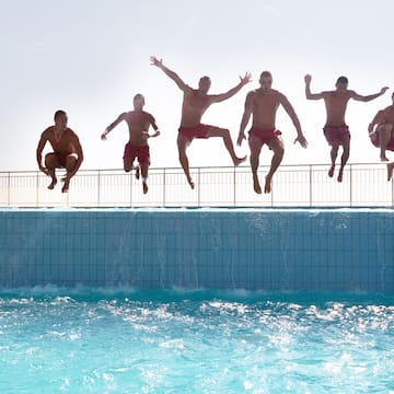 a group of men jumping into a pool