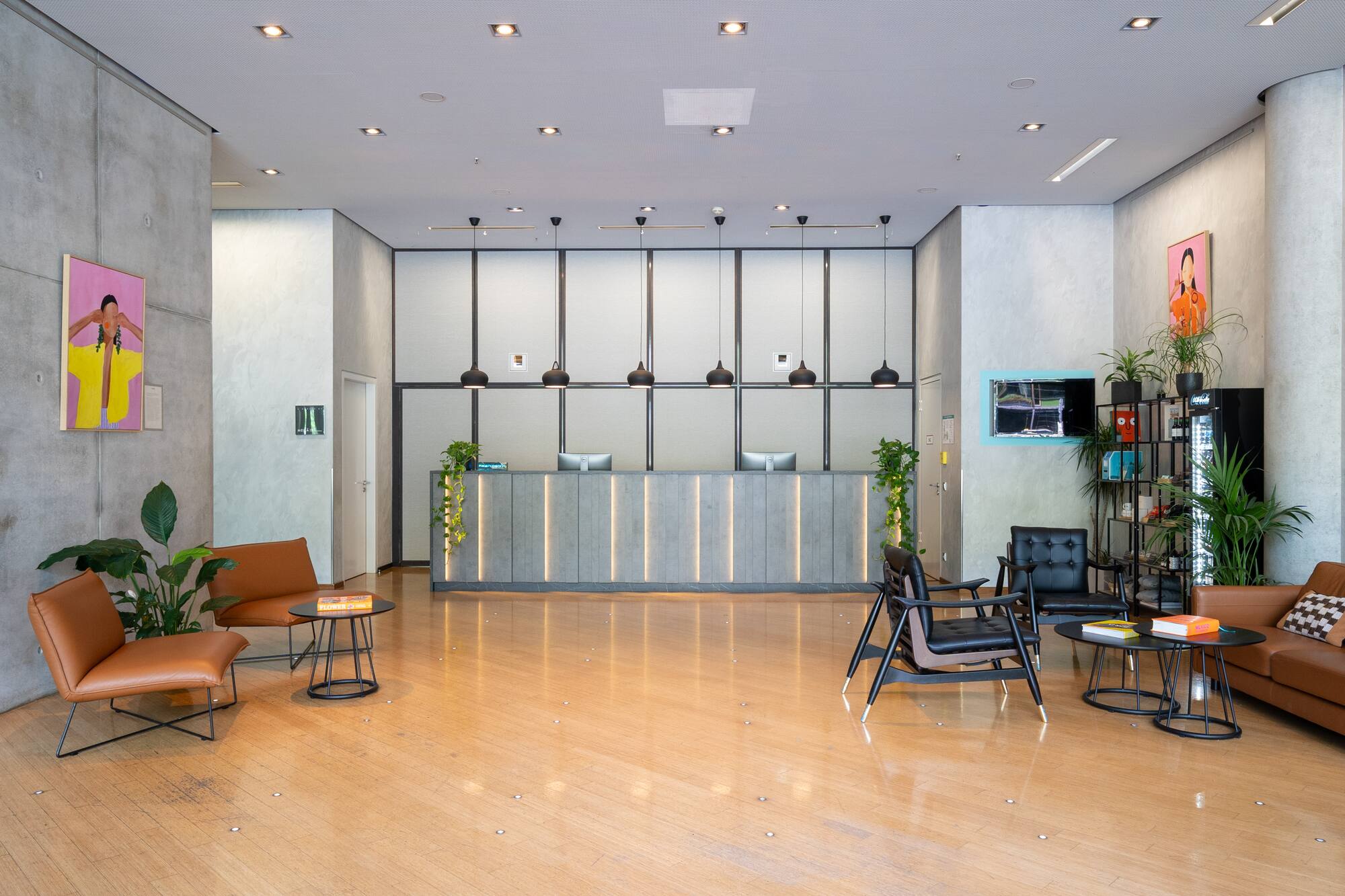 Modern hotel lobby with sleek reception desk, wooden floor, and comfortable seating areas.