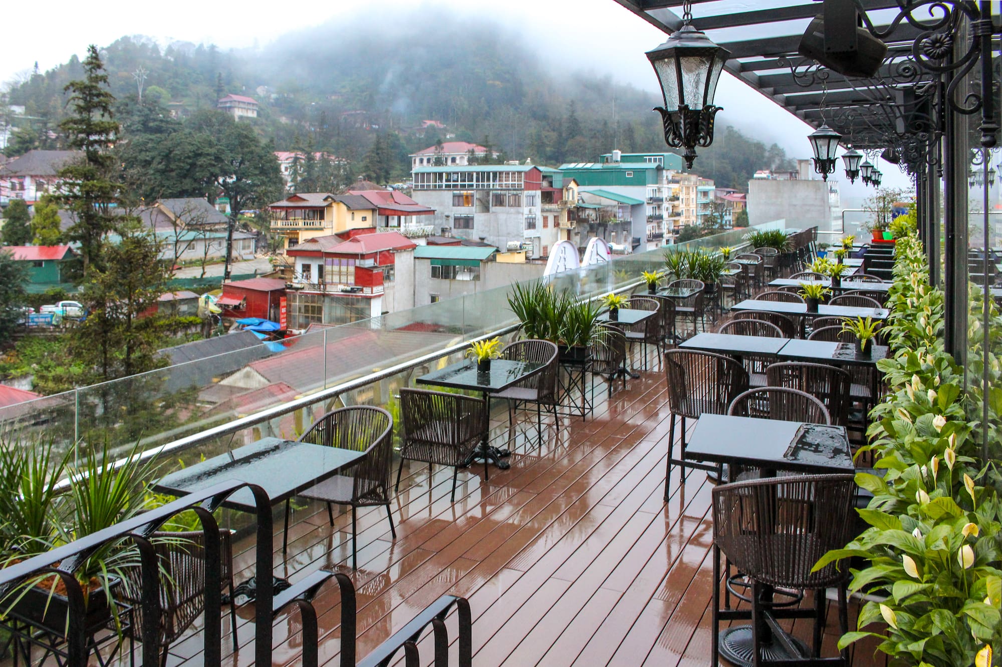 Rainy outdoor cafe terrace overlooking a misty mountain town.