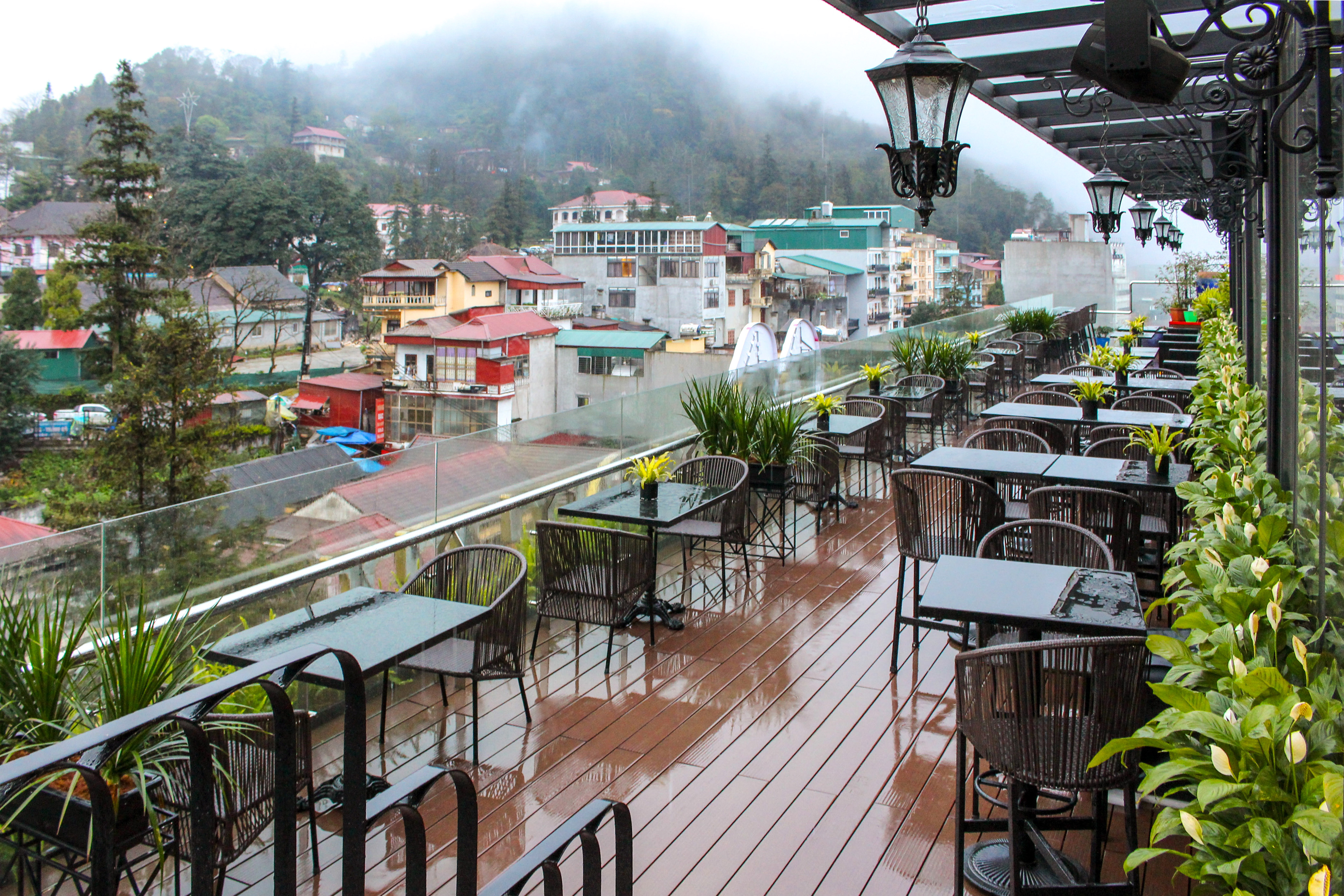 Rainy outdoor cafe terrace overlooking a misty mountain town.