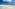 a sandy beach with blue water and clouds