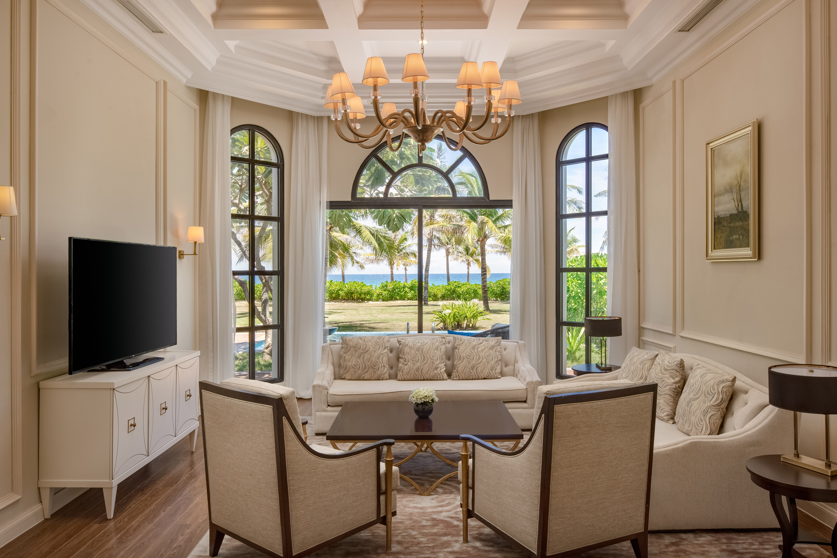 Luxury living room featuring an ocean view, palm trees, and elegant furnishings.