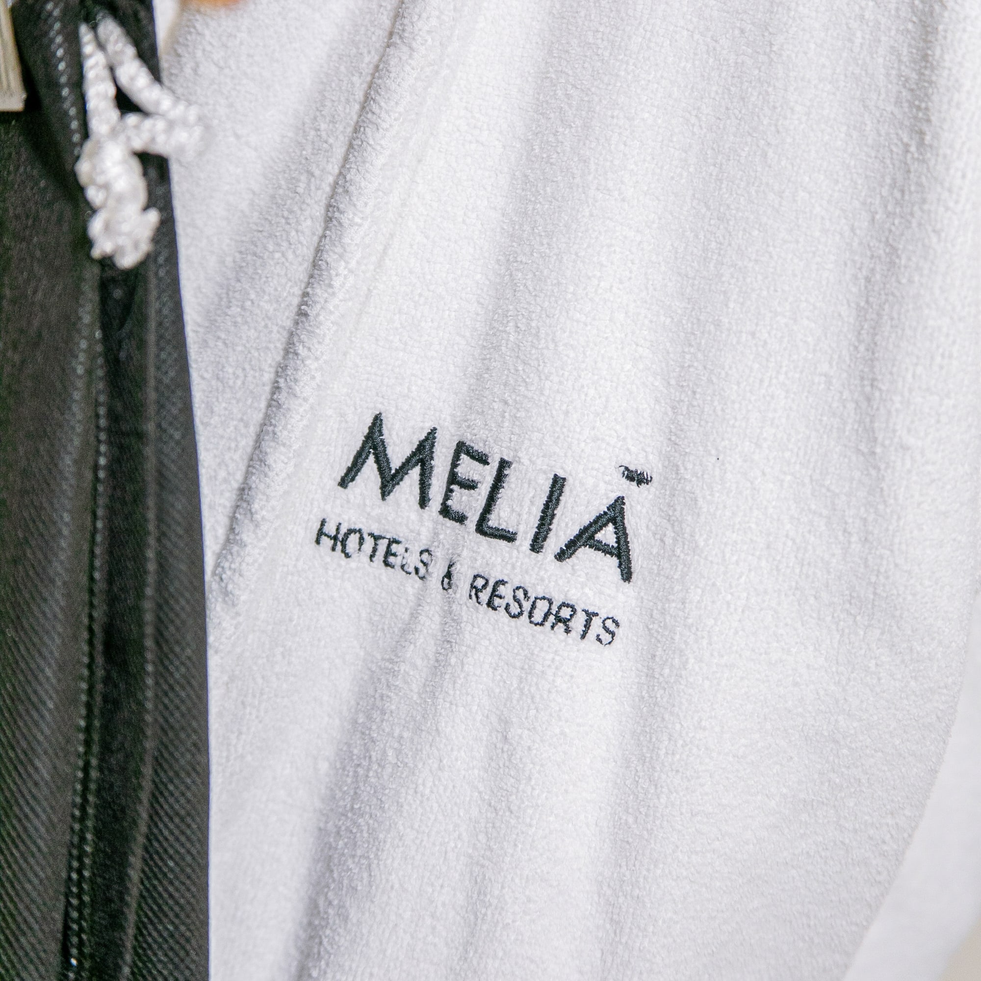 White Meliã Hotels & Resorts embroidered bathrobe, hotel amenity.
