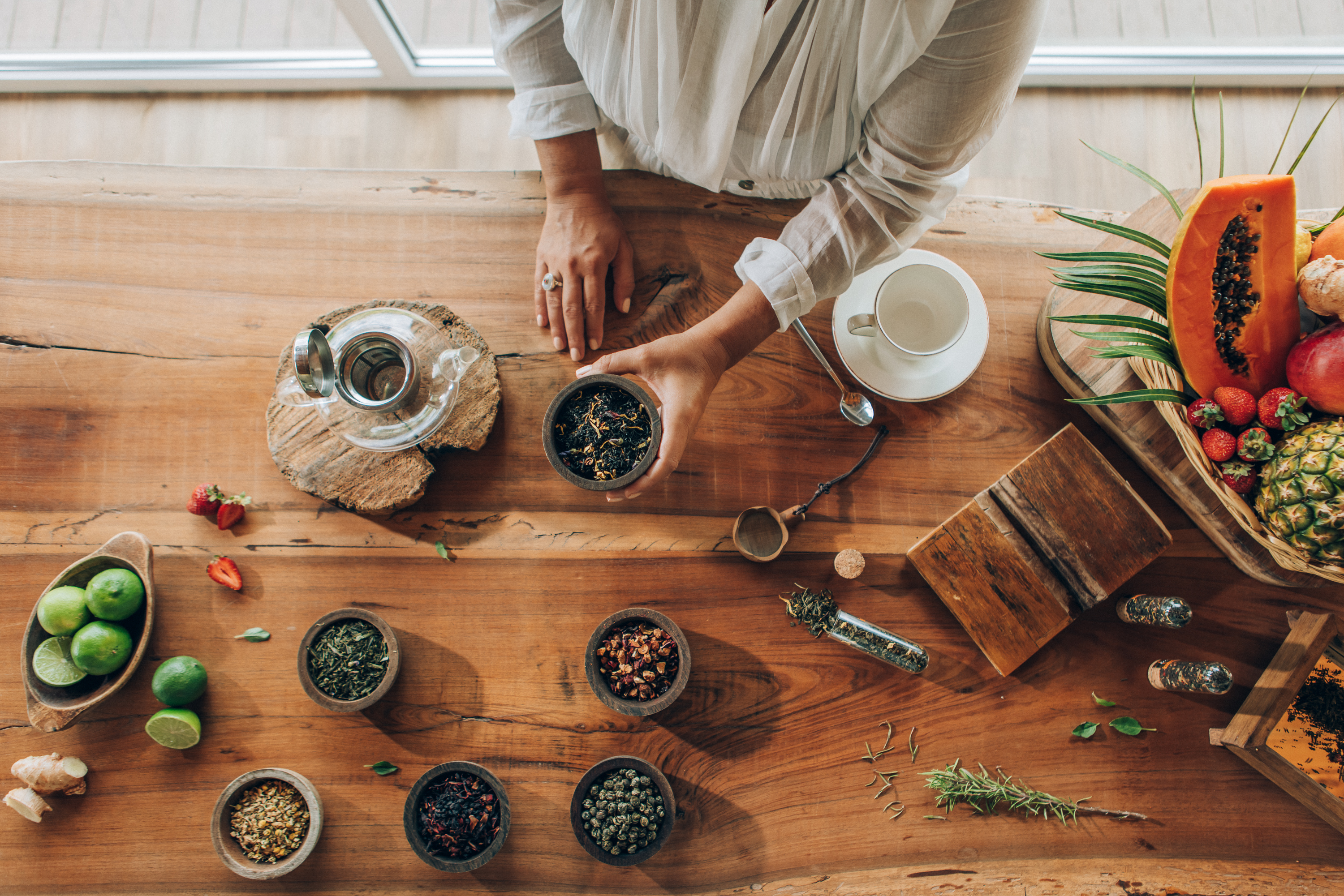 a person holding a bowl of herbs on a table