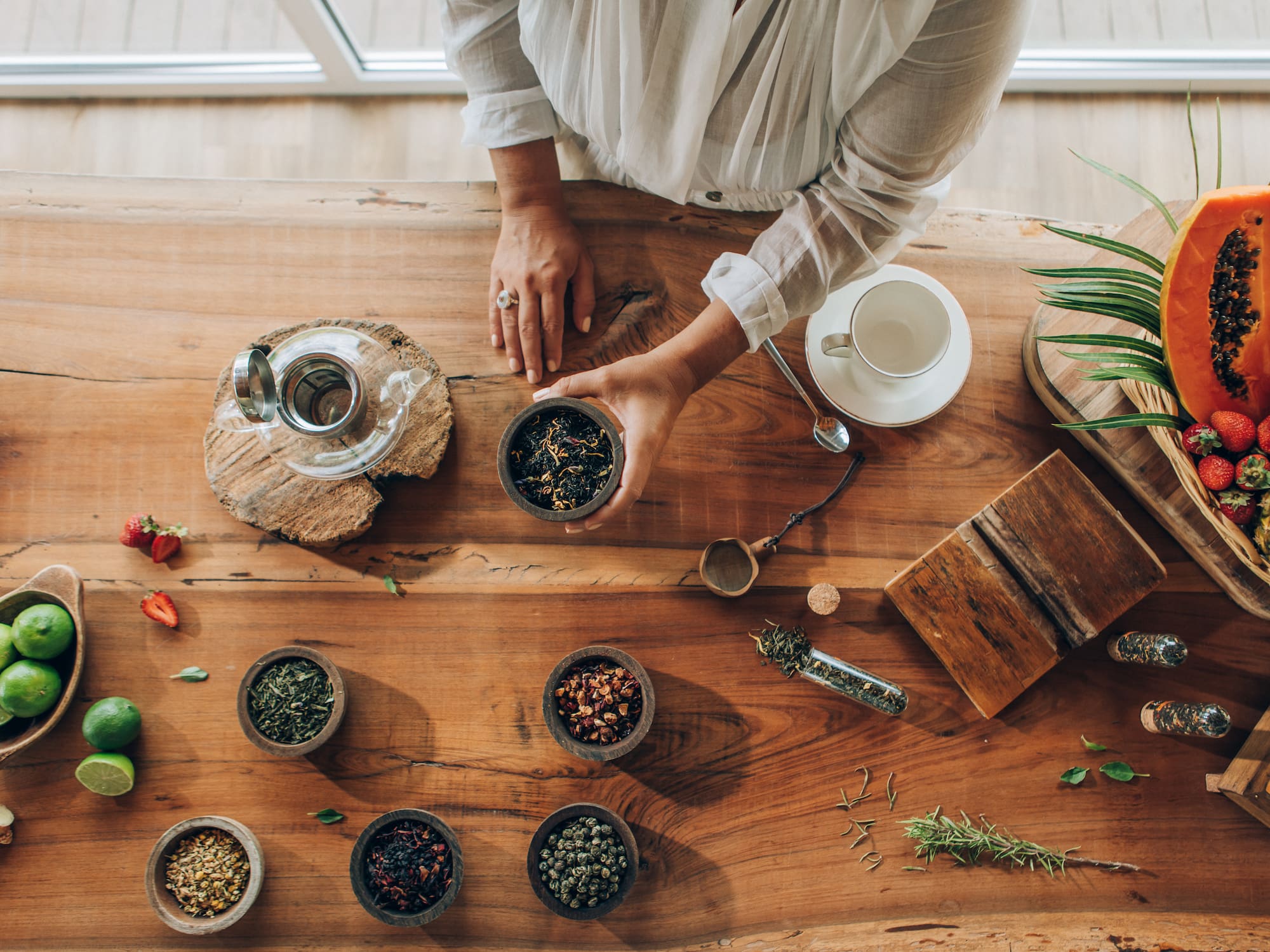 a person holding a bowl of herbs on a table