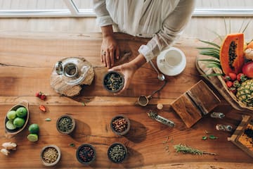 a person holding a bowl of herbs on a table