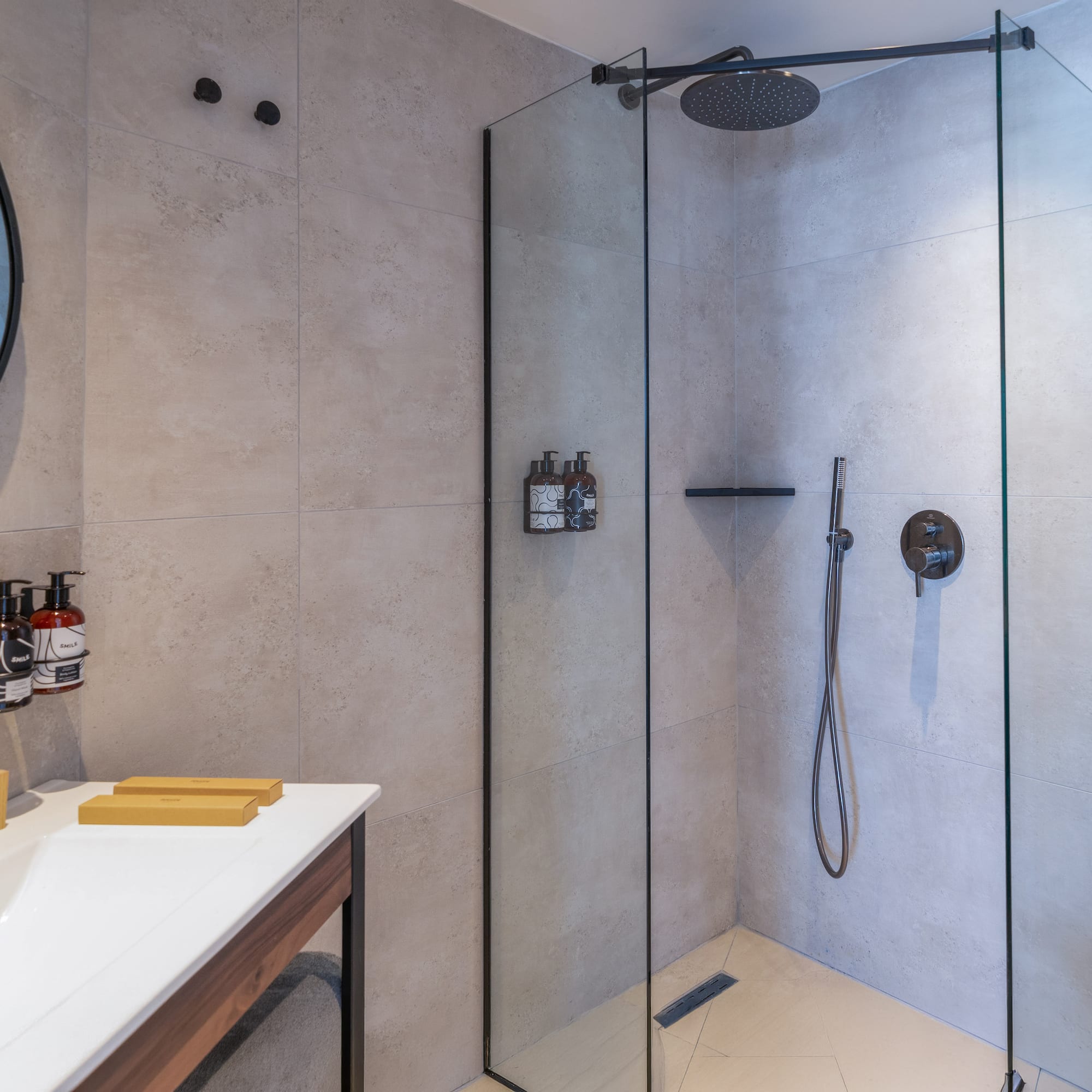 Modern bathroom with walk-in shower, rainfall head, vanity, and round mirror.
