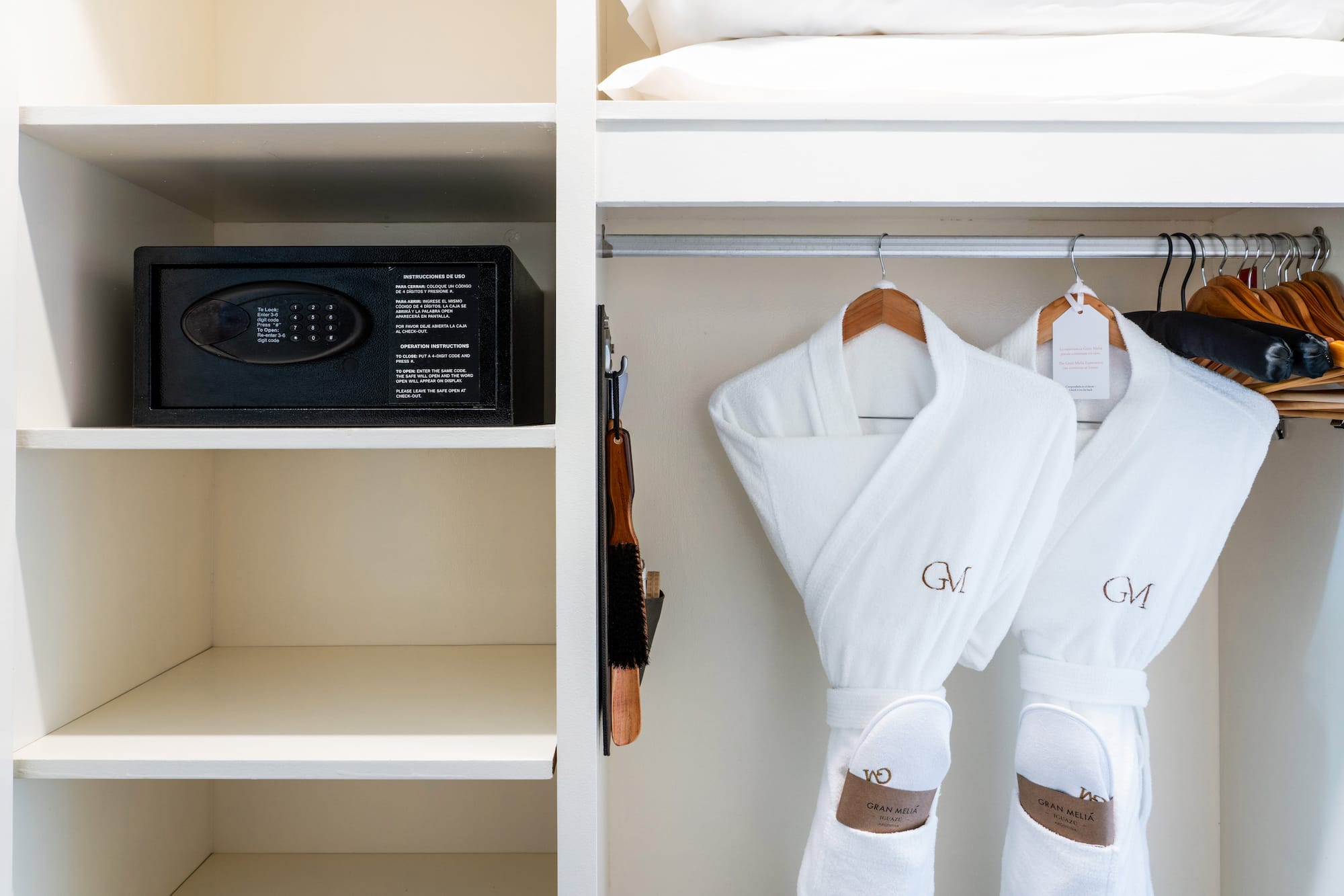 a white robe on a rack with a safe and a bed
