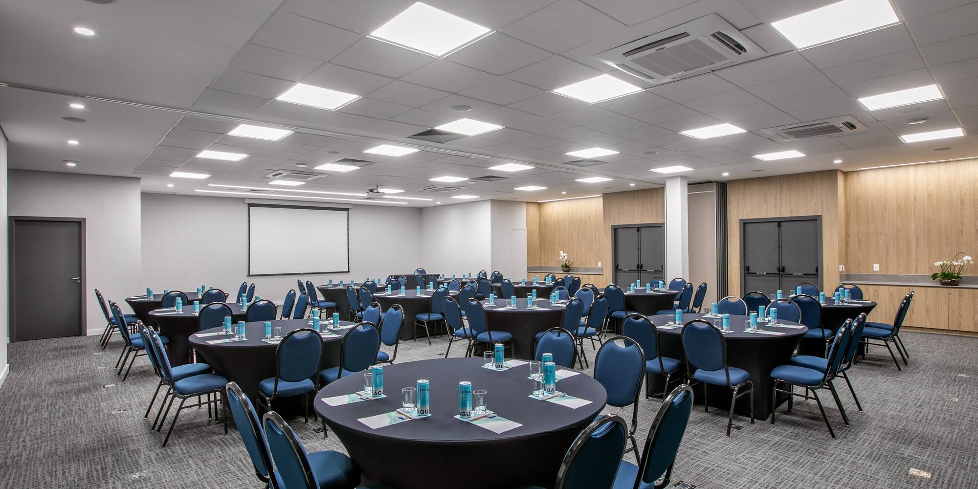 a room with round tables and blue chairs