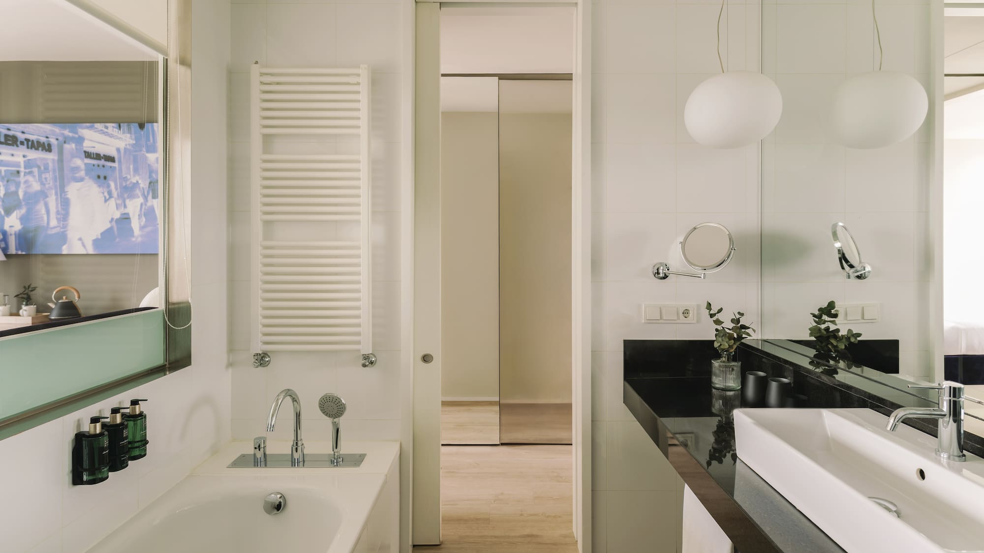 Baño moderno con bañera, lavabo blanco, encimera negra y espejo.