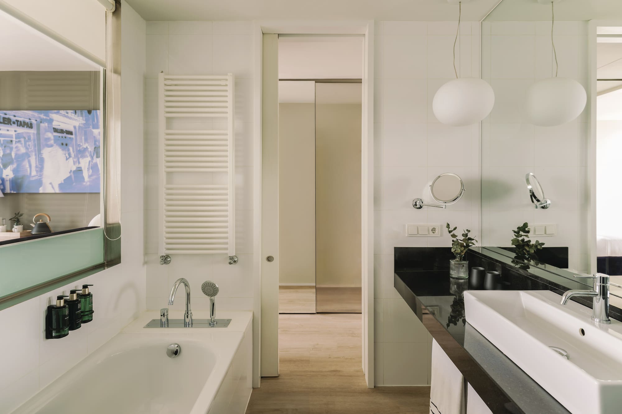 Baño moderno con bañera, lavabo blanco, encimera negra y espejo.