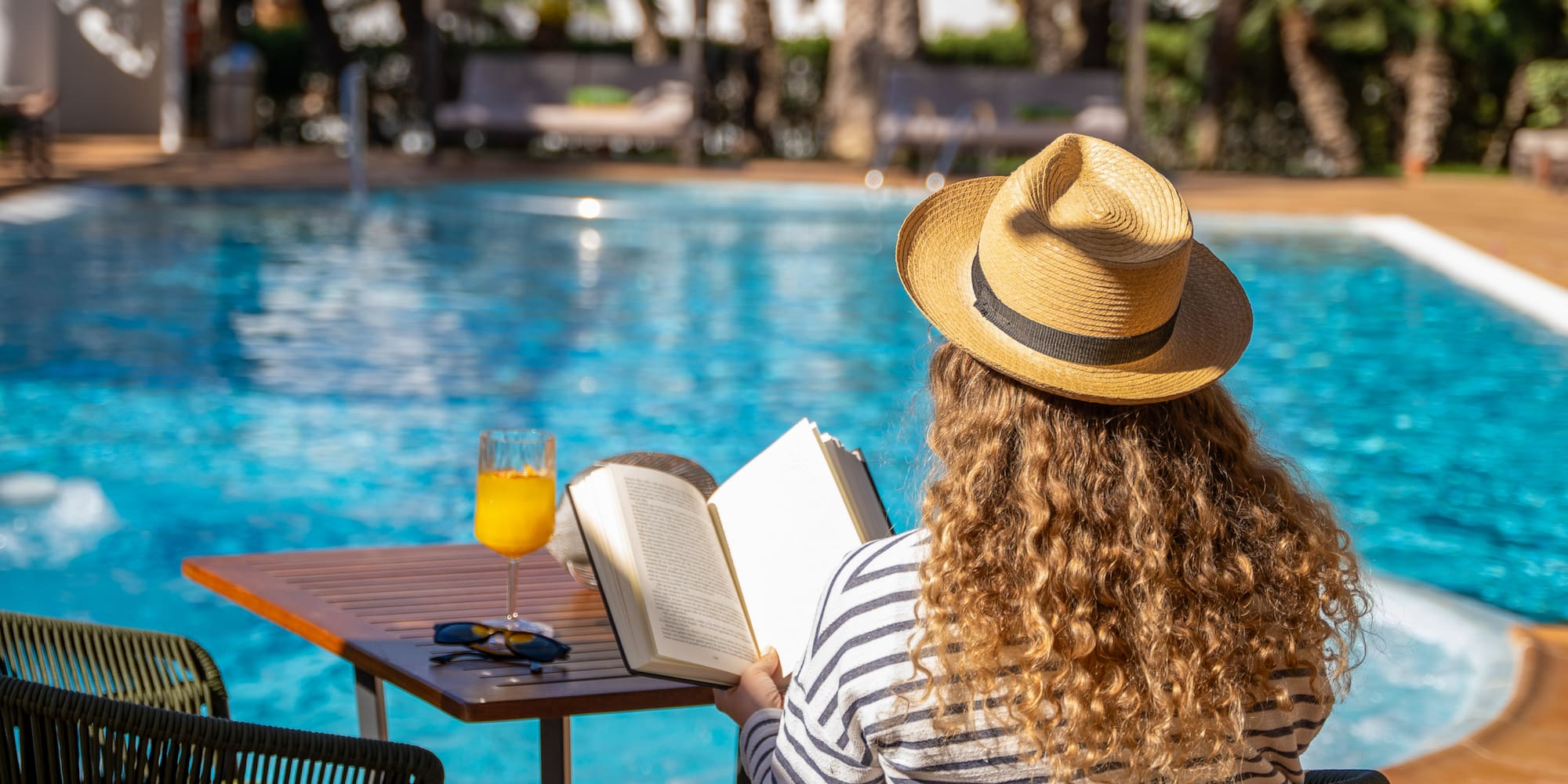 a woman sitting at a table with a book and a drink