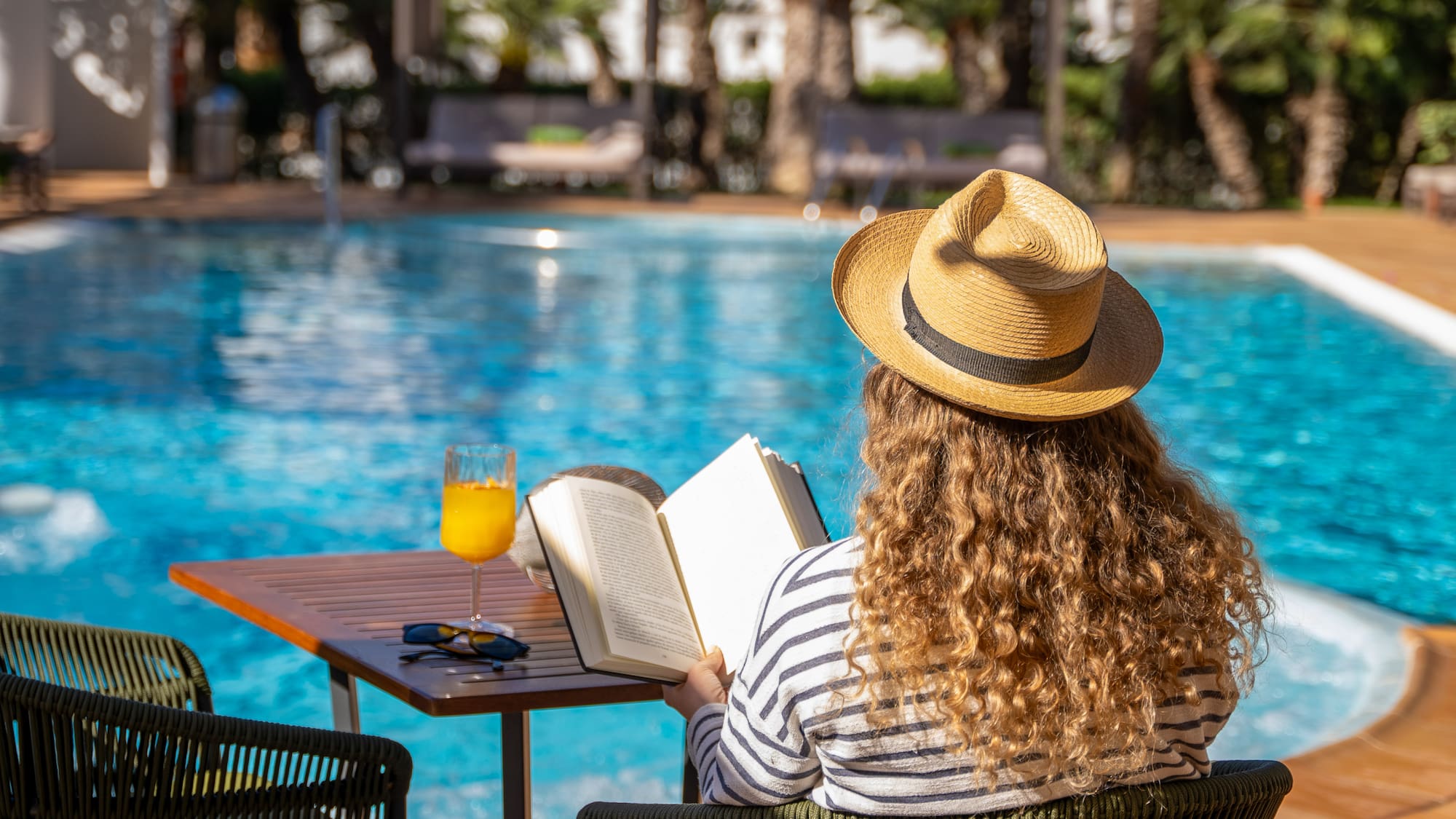 a woman sitting at a table with a book and a drink