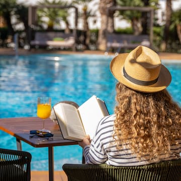 a woman sitting at a table with a book and a drink