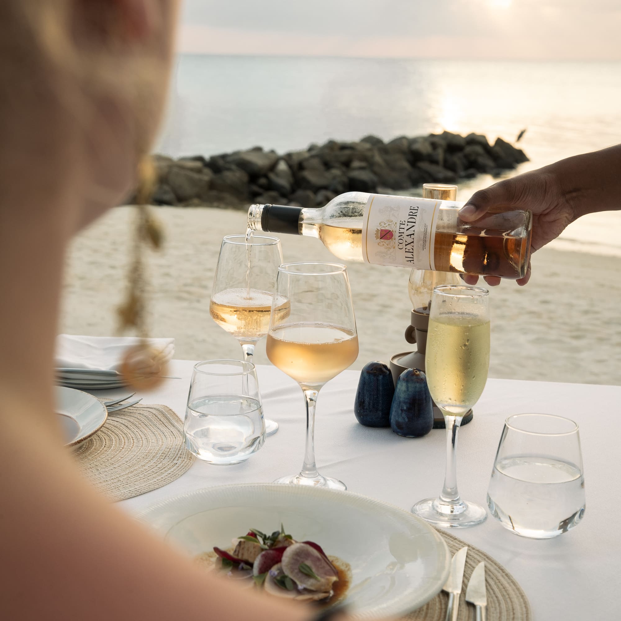 a person pouring wine into glasses on a table