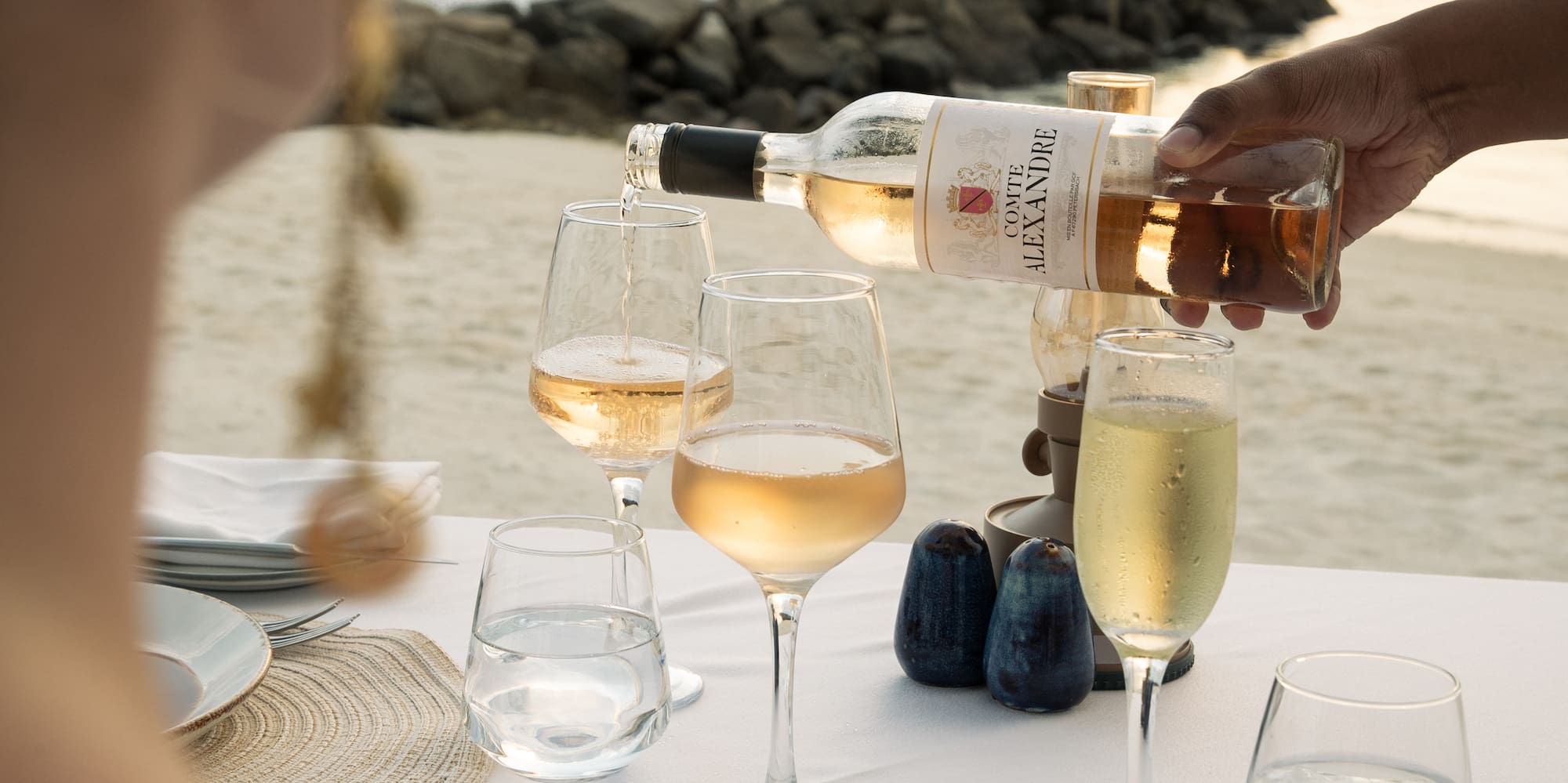 a person pouring wine into glasses on a table