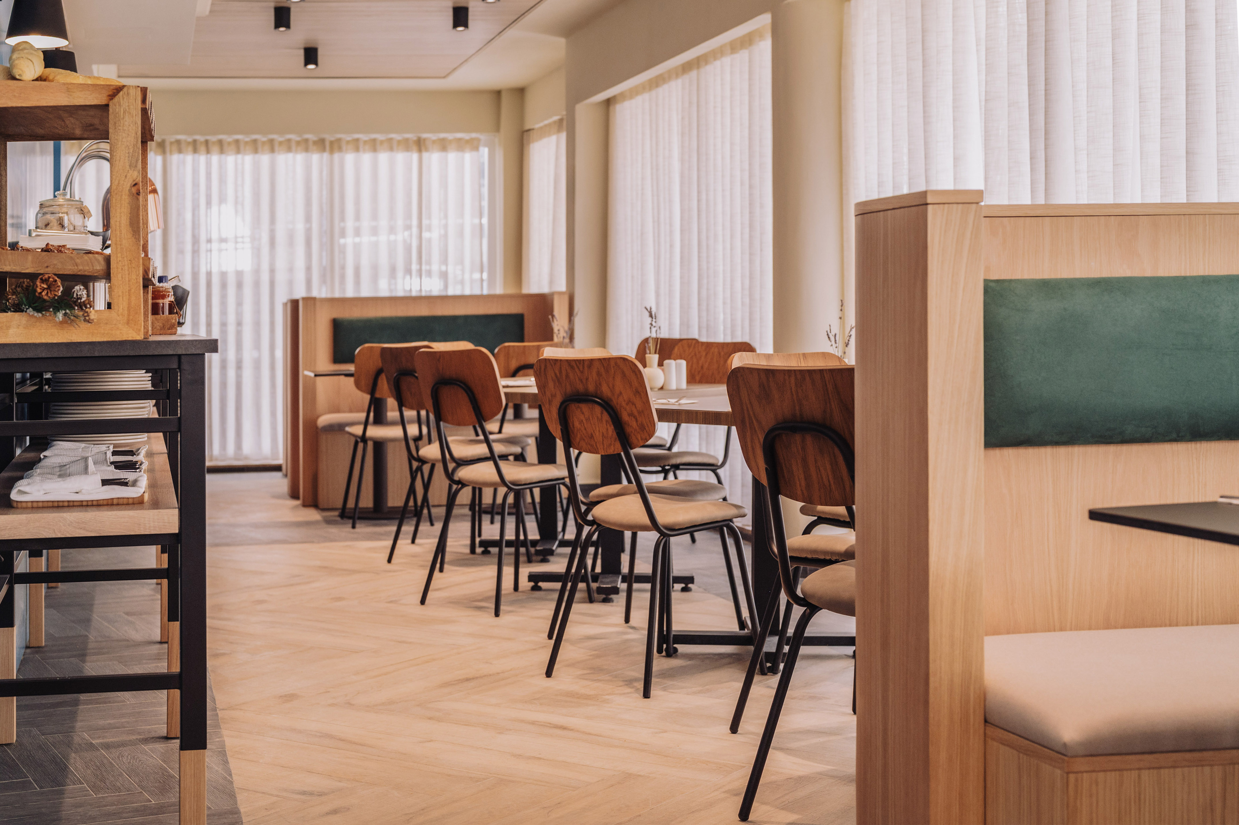 Dining interior with wooden furniture, green booths, and breakfast counter.
