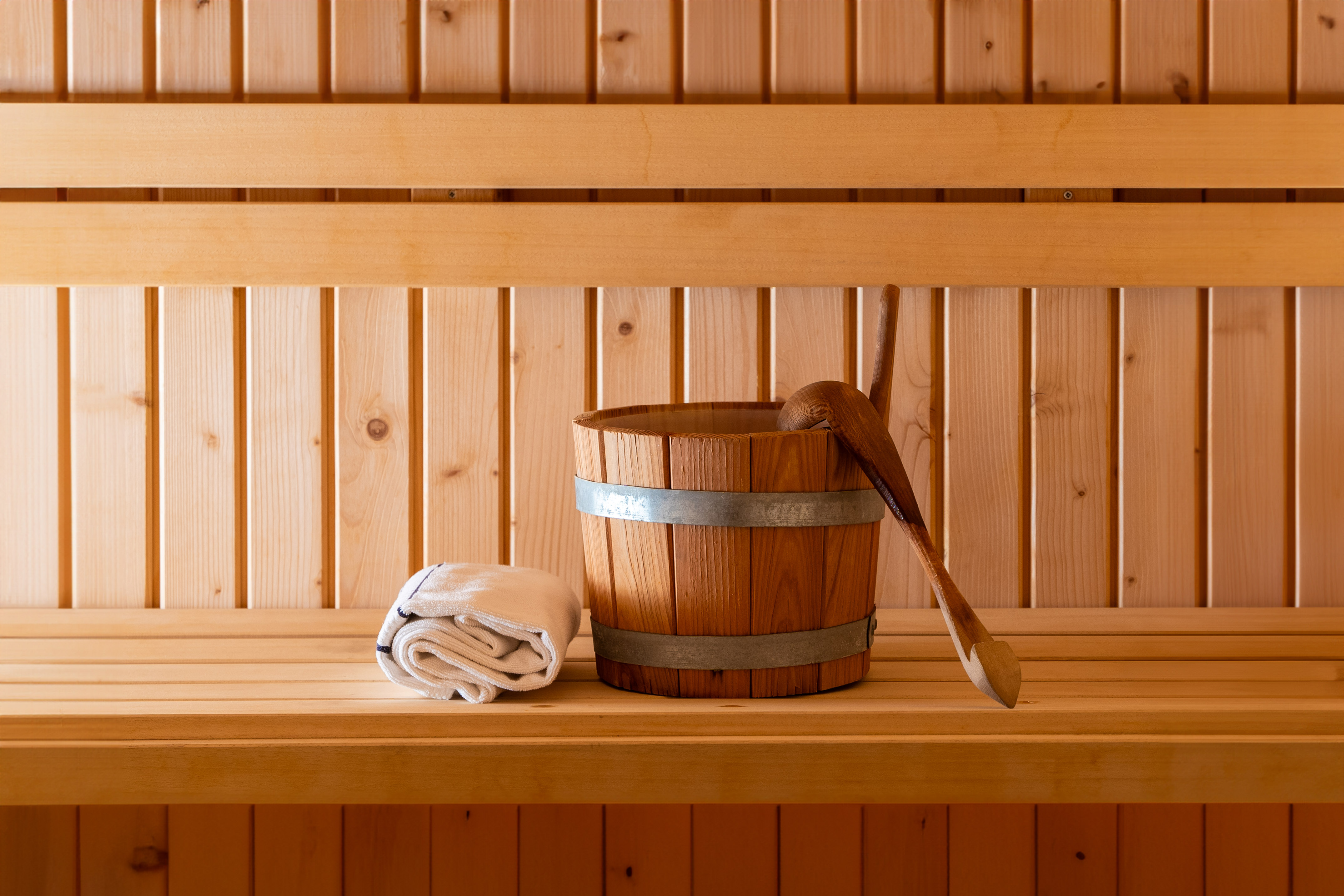 Wooden sauna interior with bucket, ladle, and folded white towel on a bench. - Area benessere - Meliá Cala d'Or Boutique Hotel, Maiorca