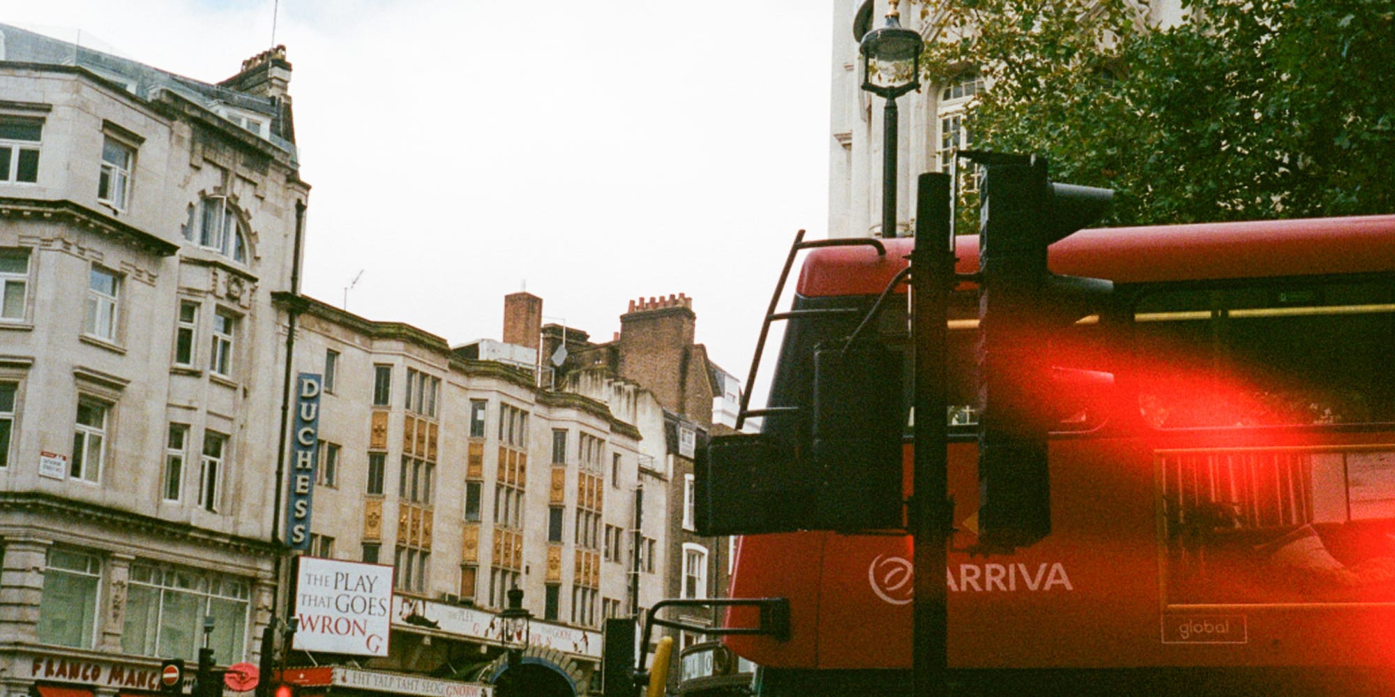 a red double decker bus on a street in a city