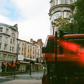 a red double decker bus on a street in a city