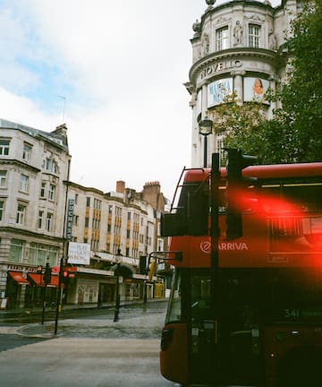 a red double decker bus on a street in a city