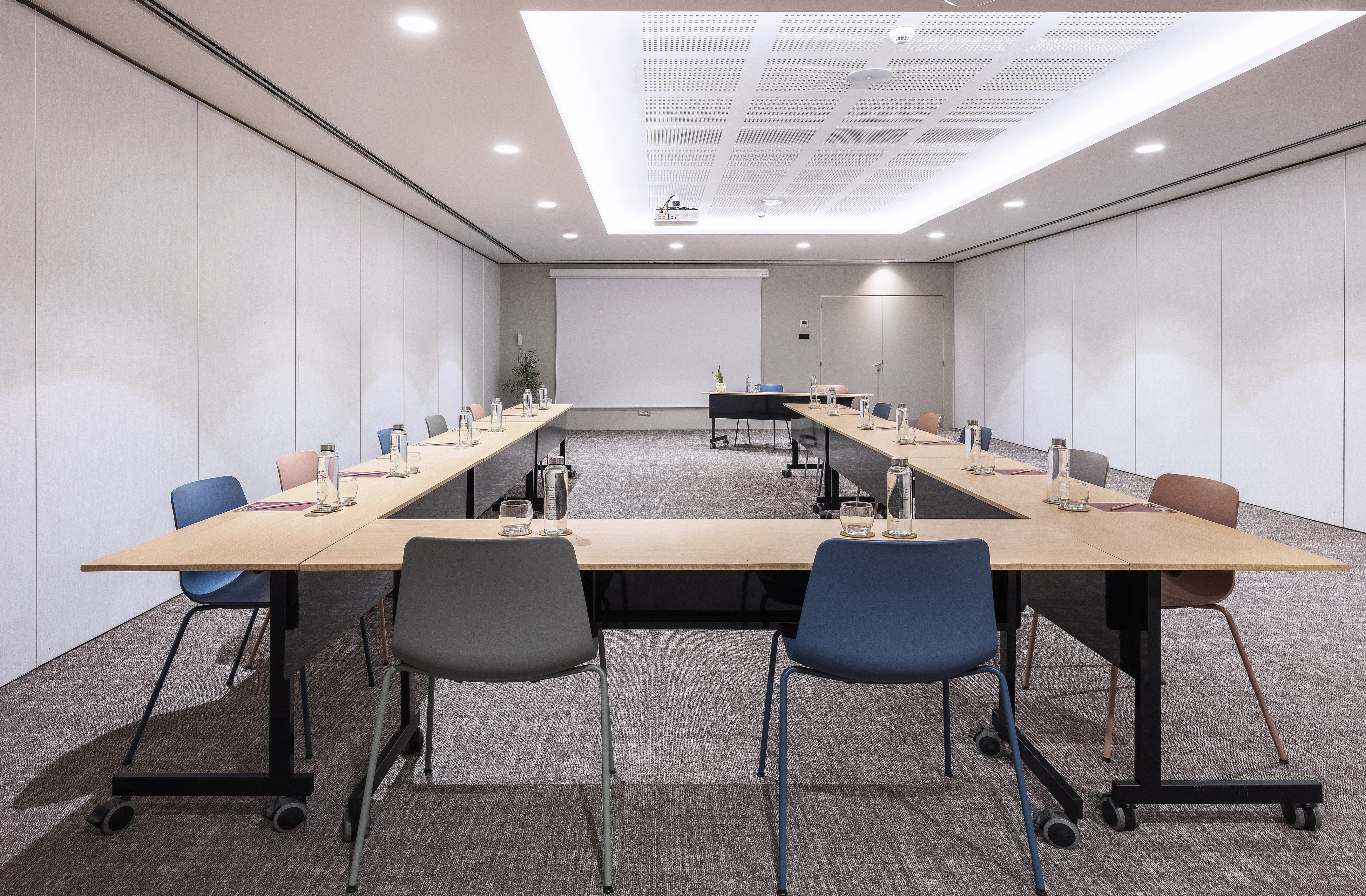 Modern conference room with U-shape table setup and projector screen.