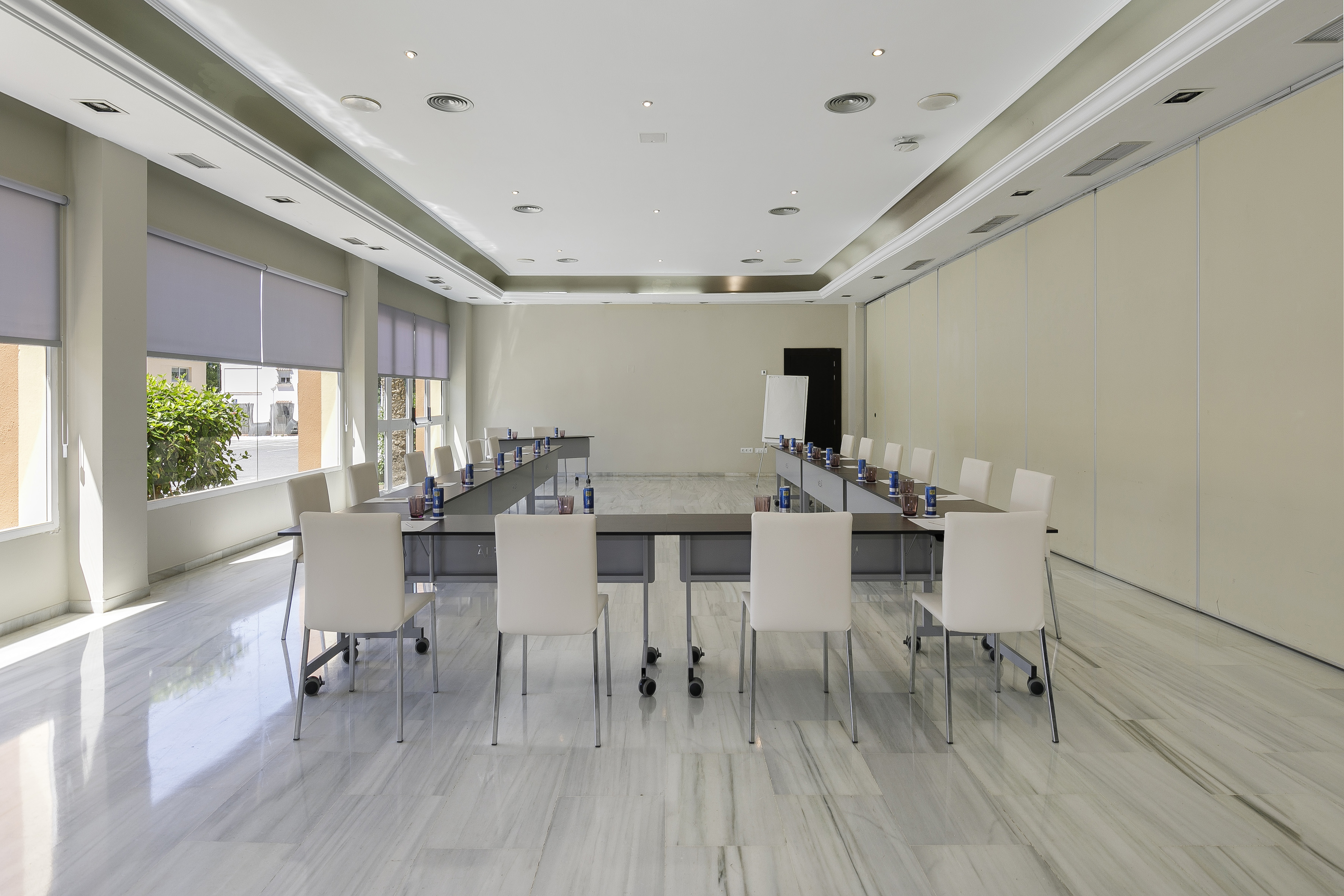 U-shaped meeting room with white chairs, marble floor, and large windows.