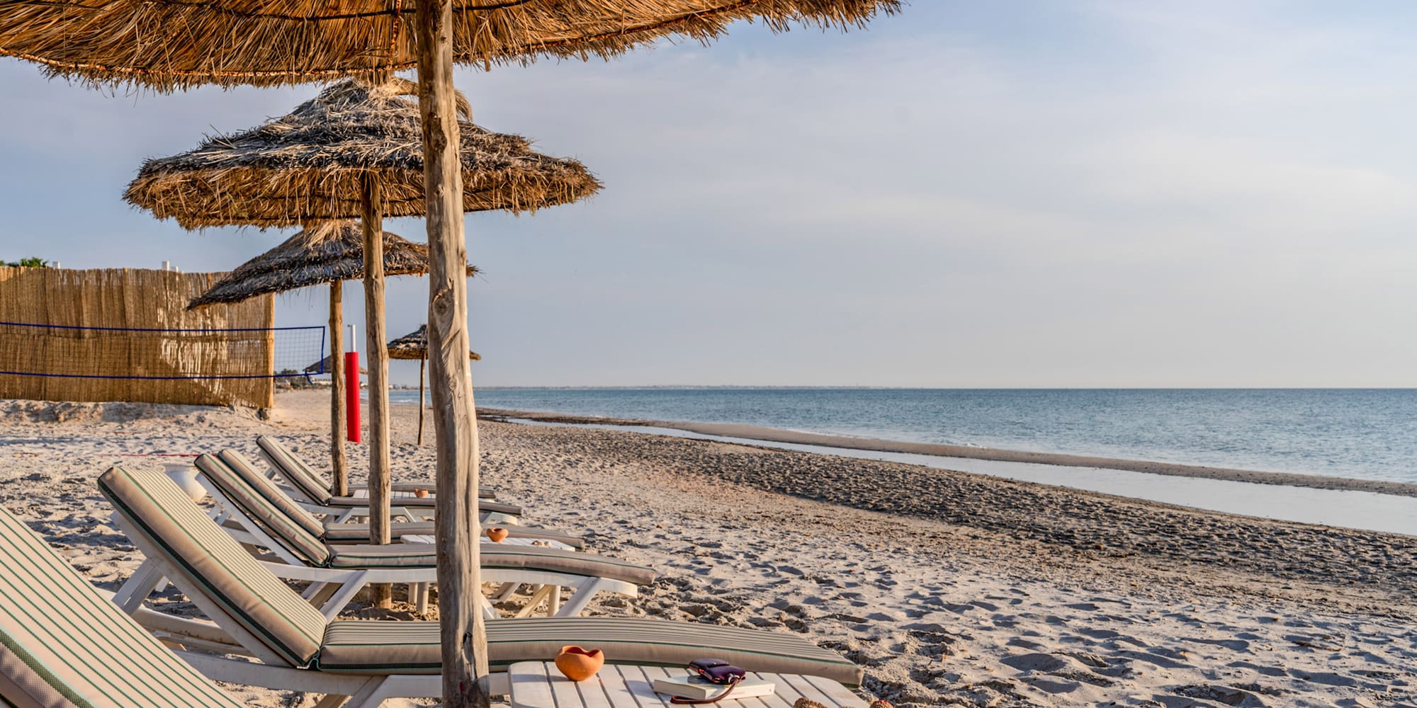 Beach resort with thatched umbrellas, sunbeds, and ocean vista.