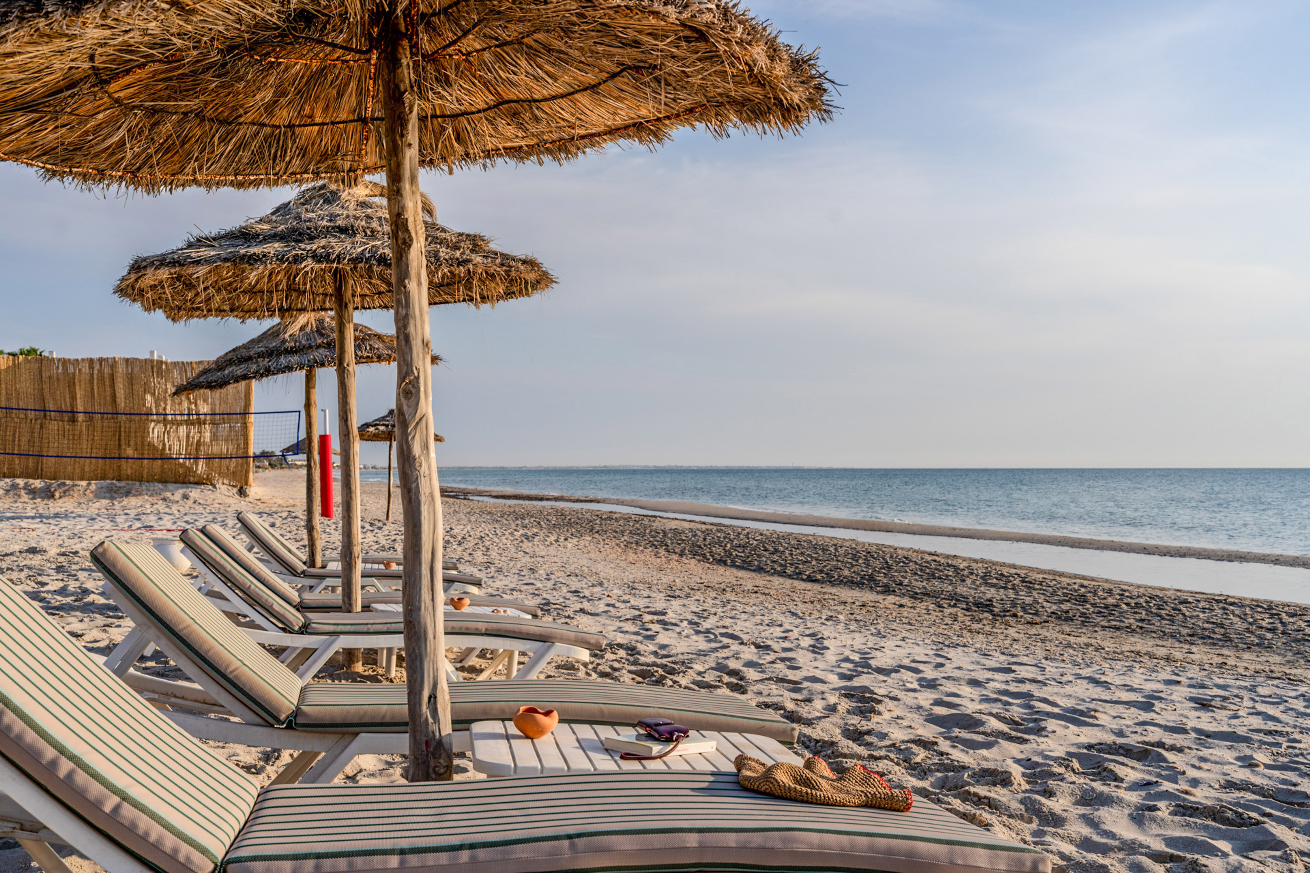 Beach resort with thatched umbrellas, sunbeds, and ocean vista.