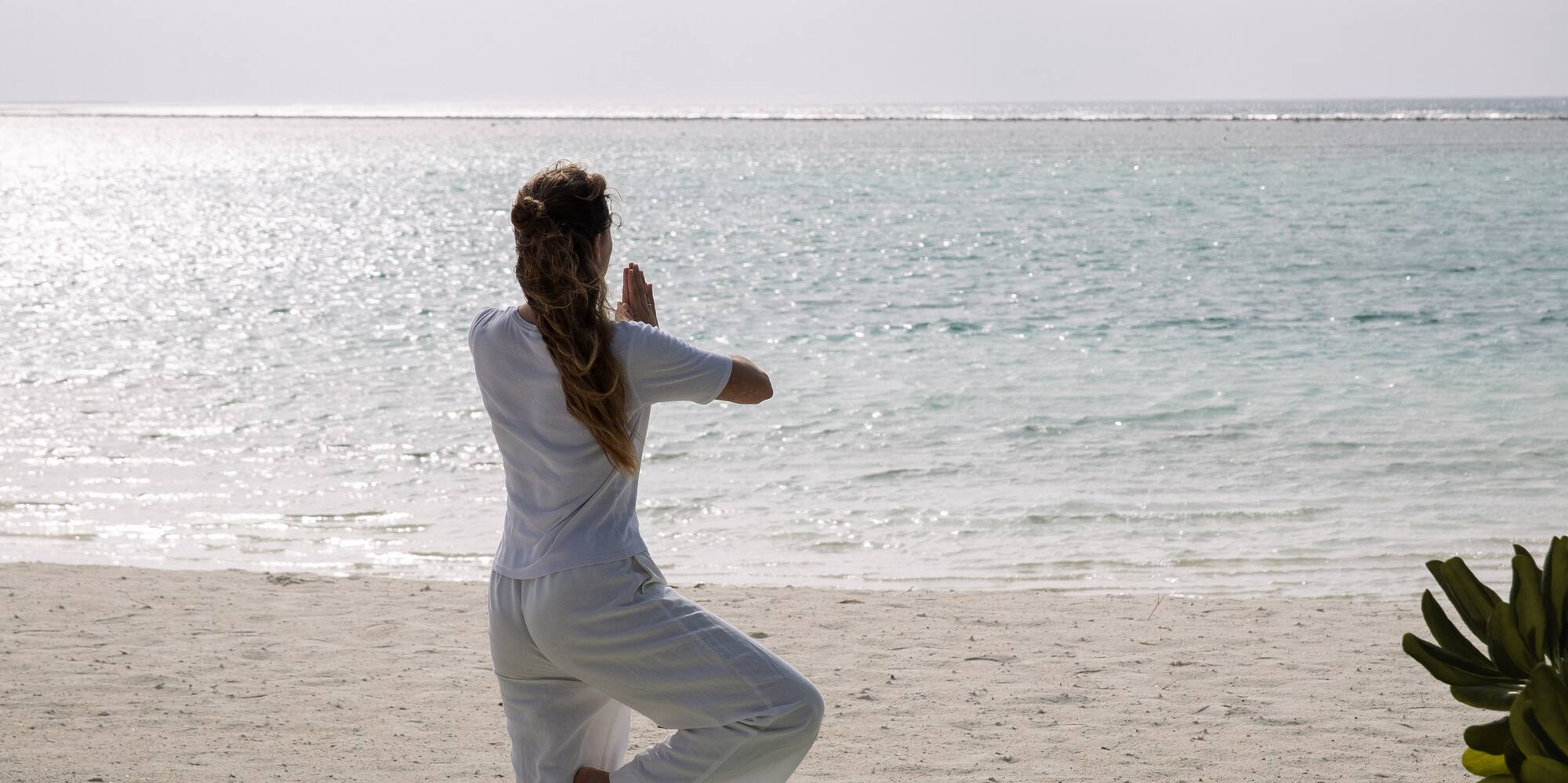 a woman standing on a yoga mat on a beach