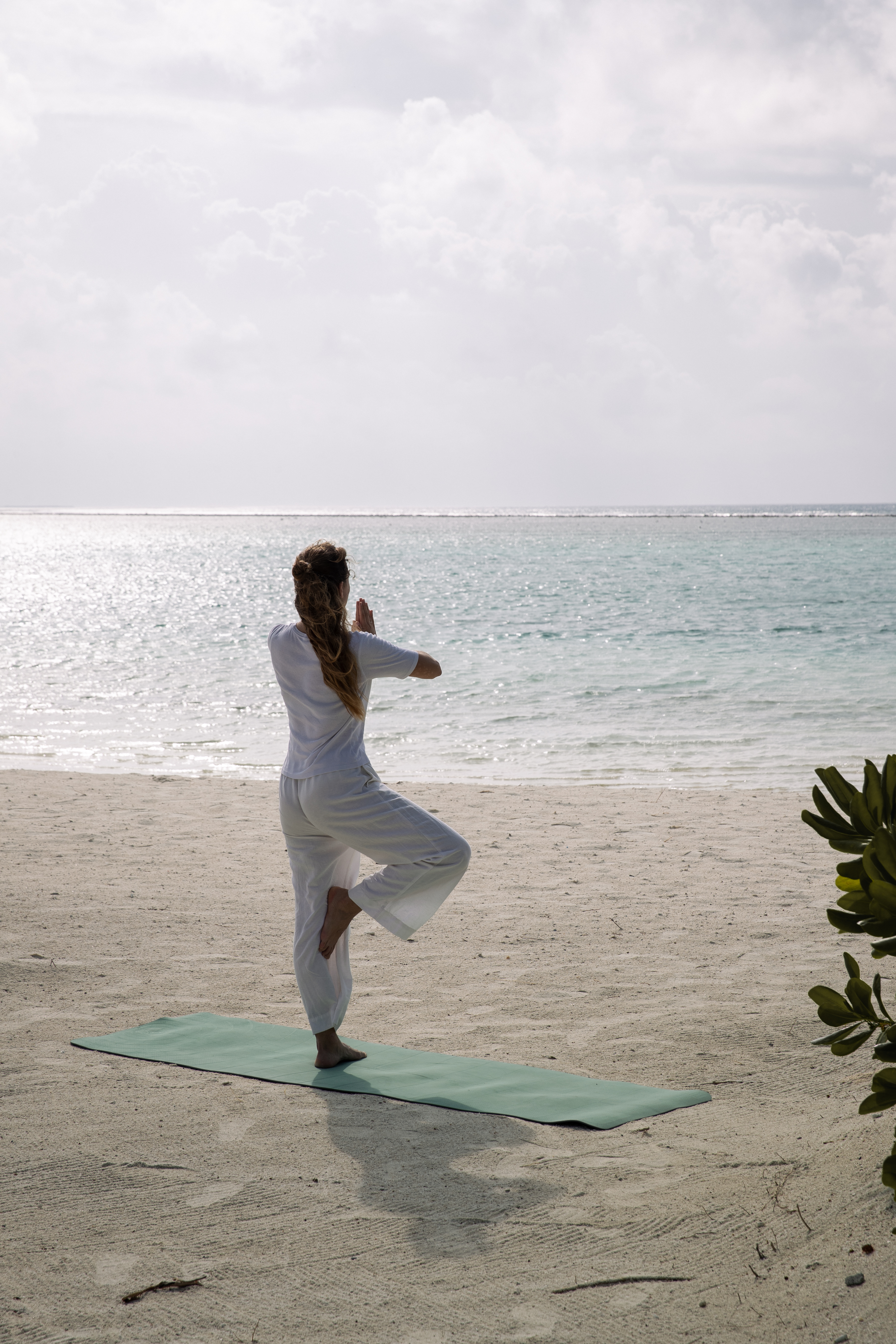 a woman standing on a yoga mat on a beach