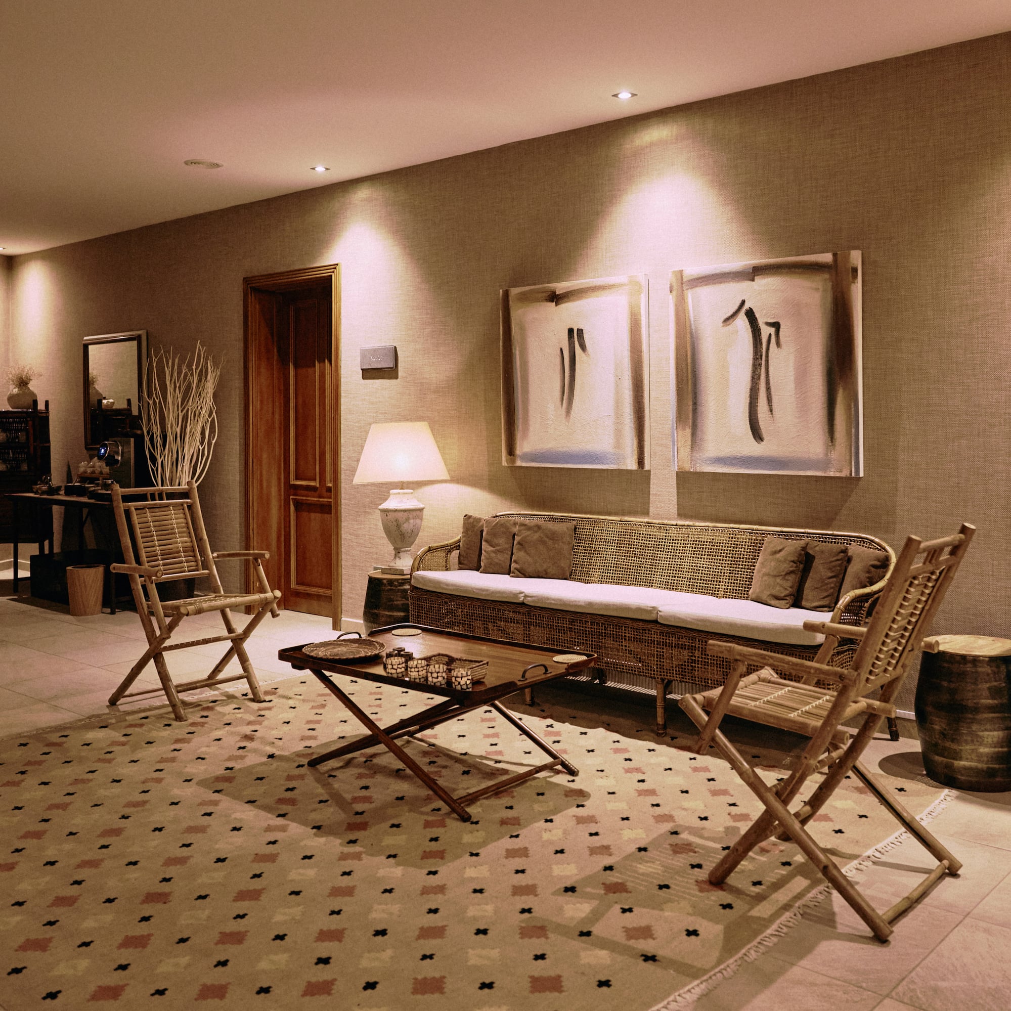Spa lounge with rattan sofa, folding chairs, patterned rug, and display.