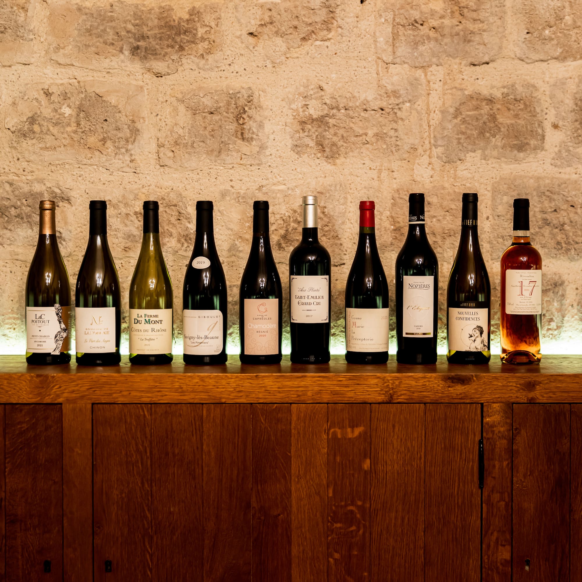 a row of wine bottles on a wooden shelf