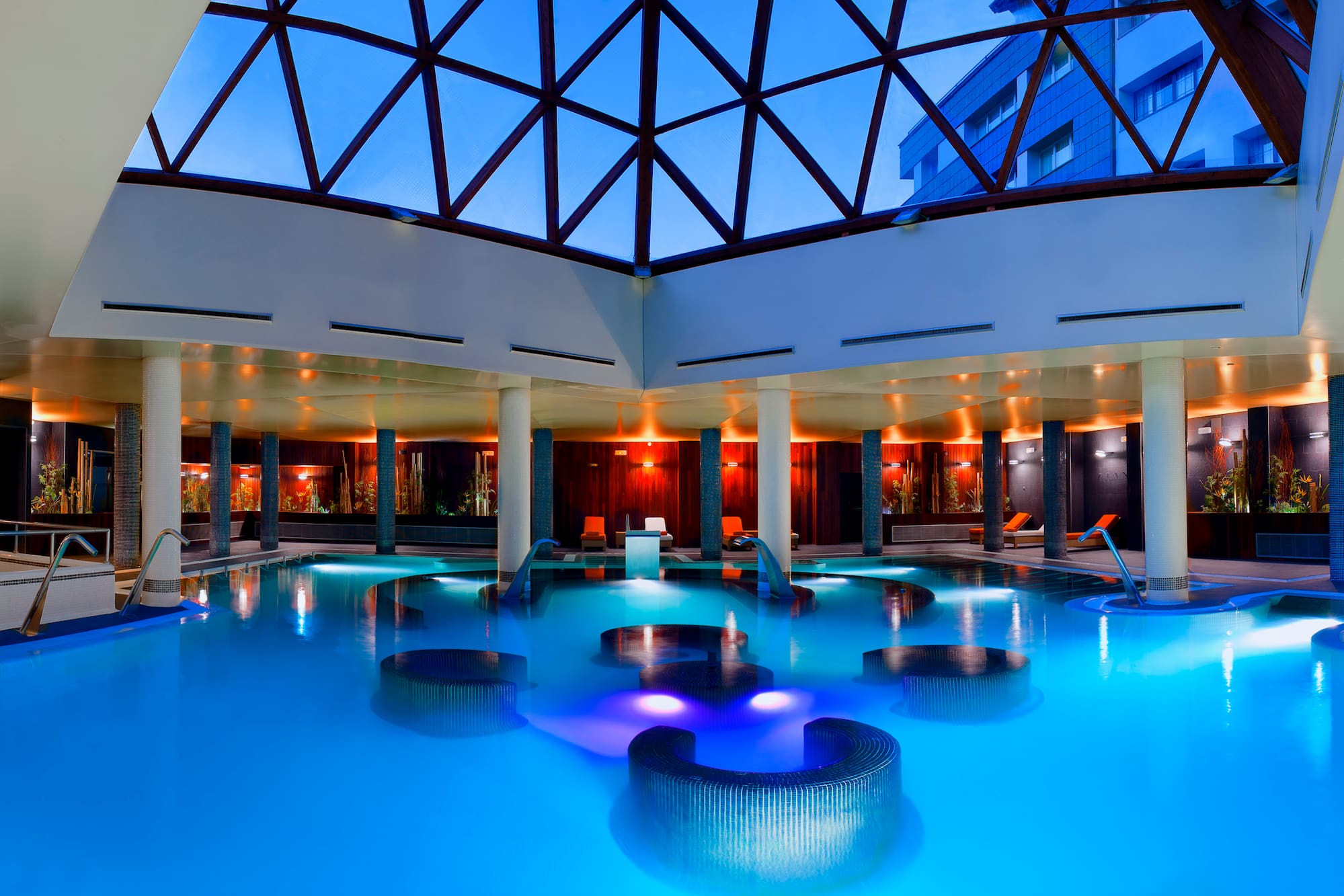 a pool with chairs and a glass roof