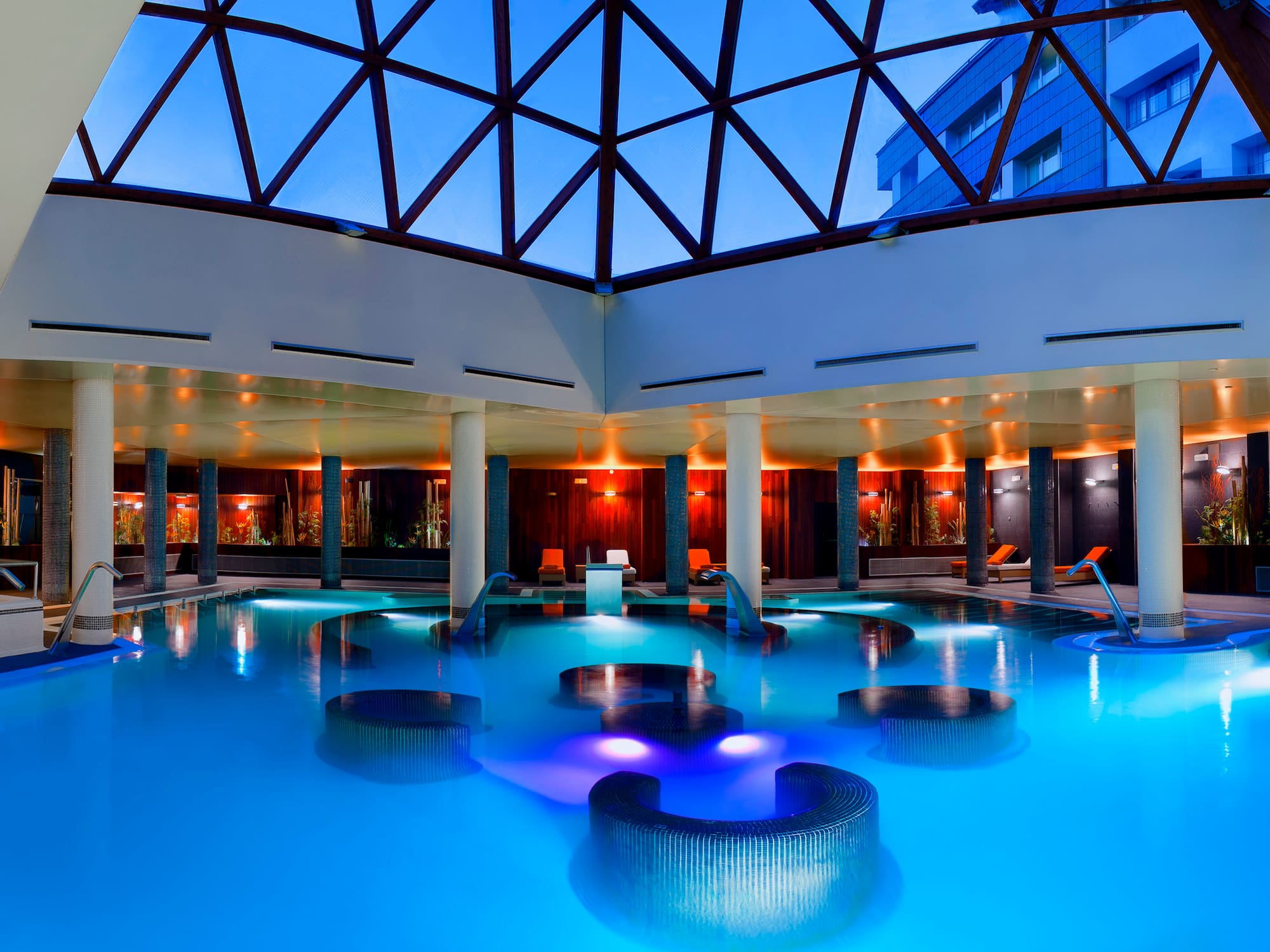 a pool with chairs and a glass roof