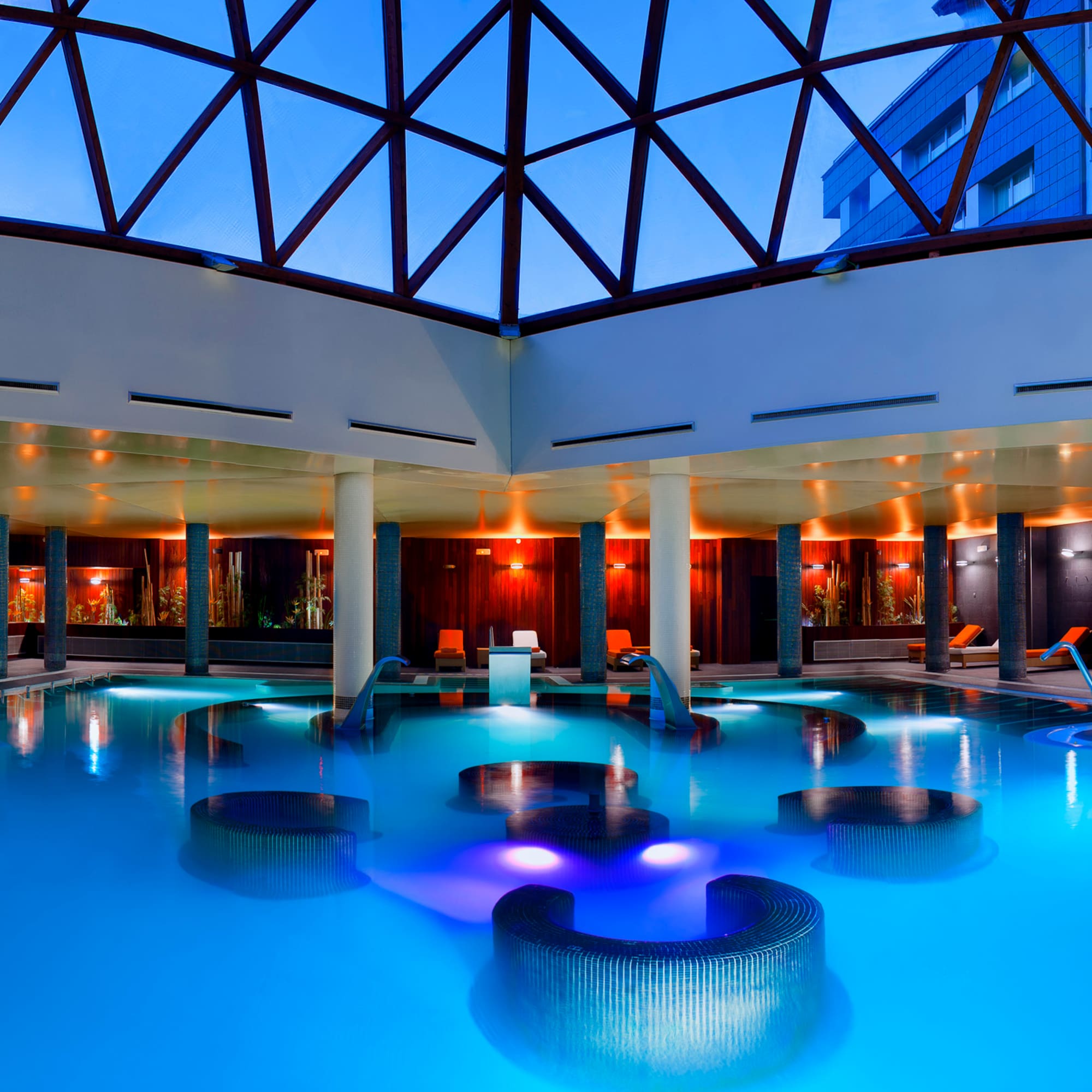 a pool with chairs and a glass roof