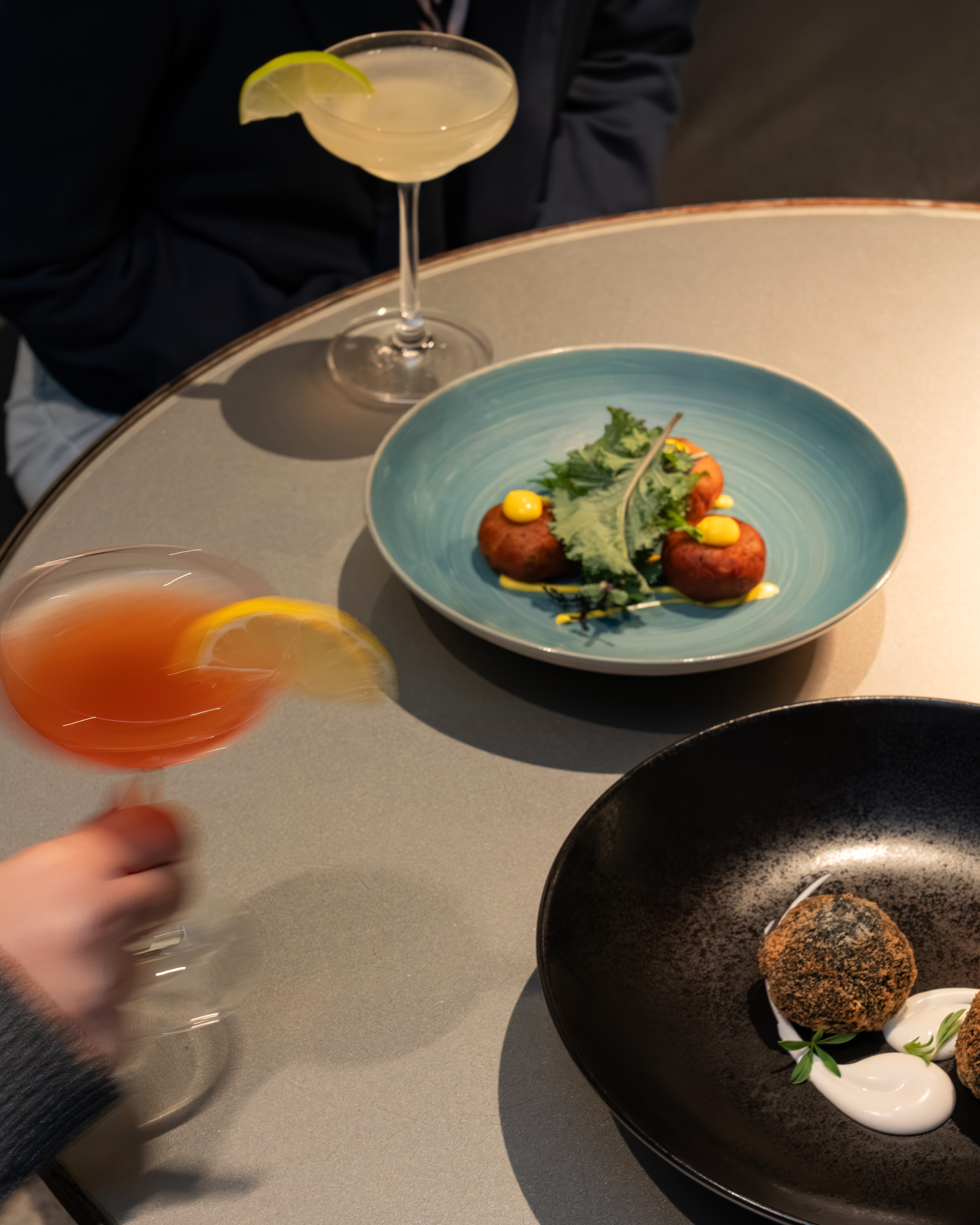 Cocktails and diverse appetizers on a modern restaurant table.