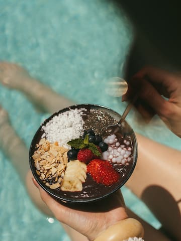 a bowl of fruit and nuts in a person's hands