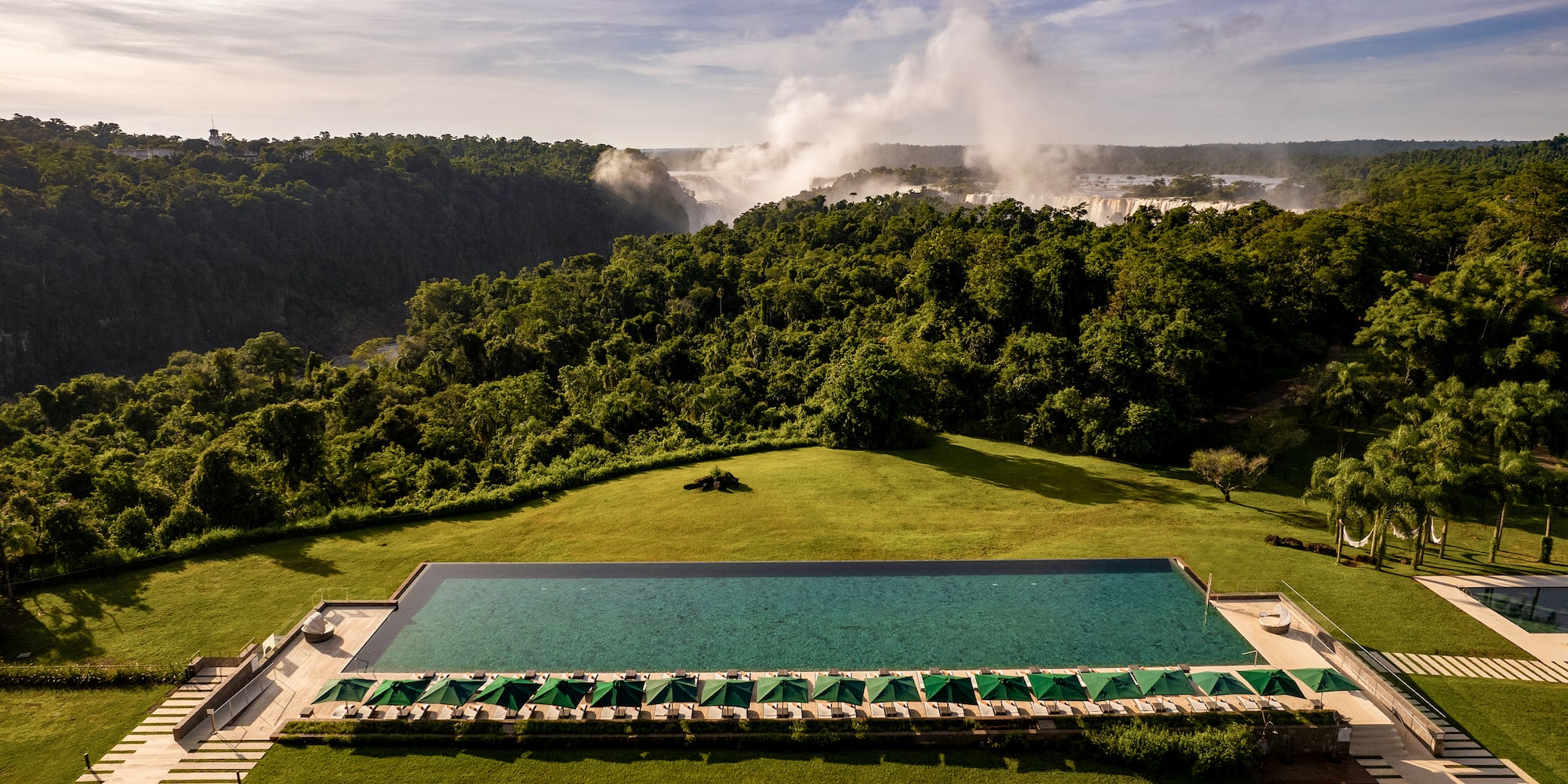 Luxury resort infinity pool with Iguazu Falls and rainforest view.
