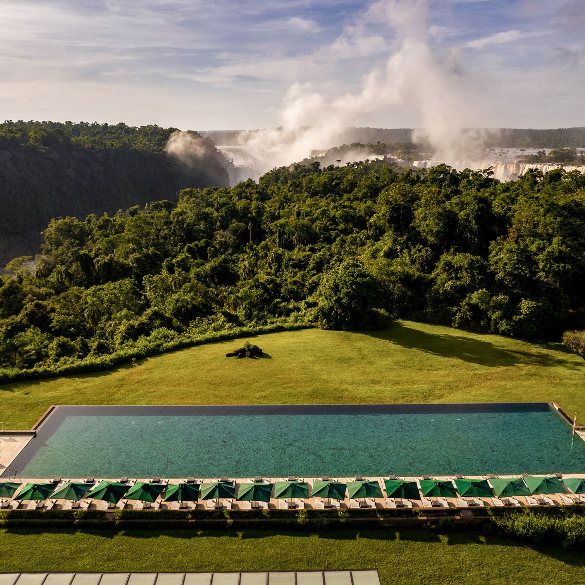 Luxury resort infinity pool with Iguazu Falls and rainforest view.
