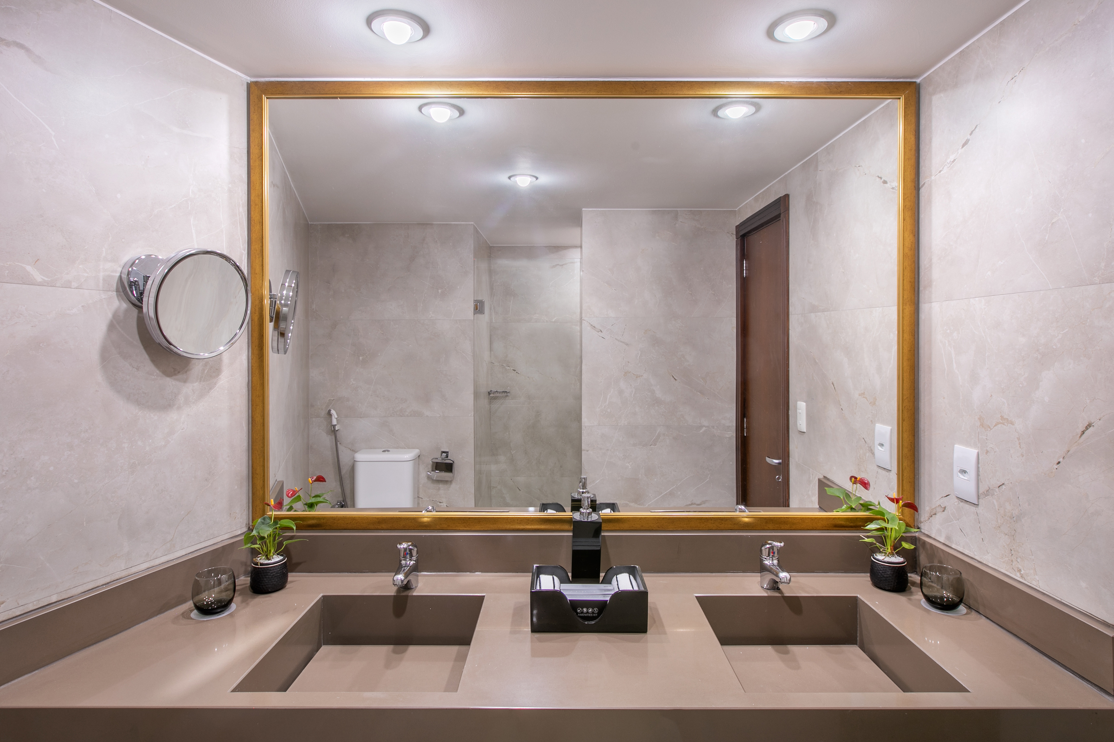 Stylish double sink bathroom vanity, gold mirror, gray walls, contemporary design.