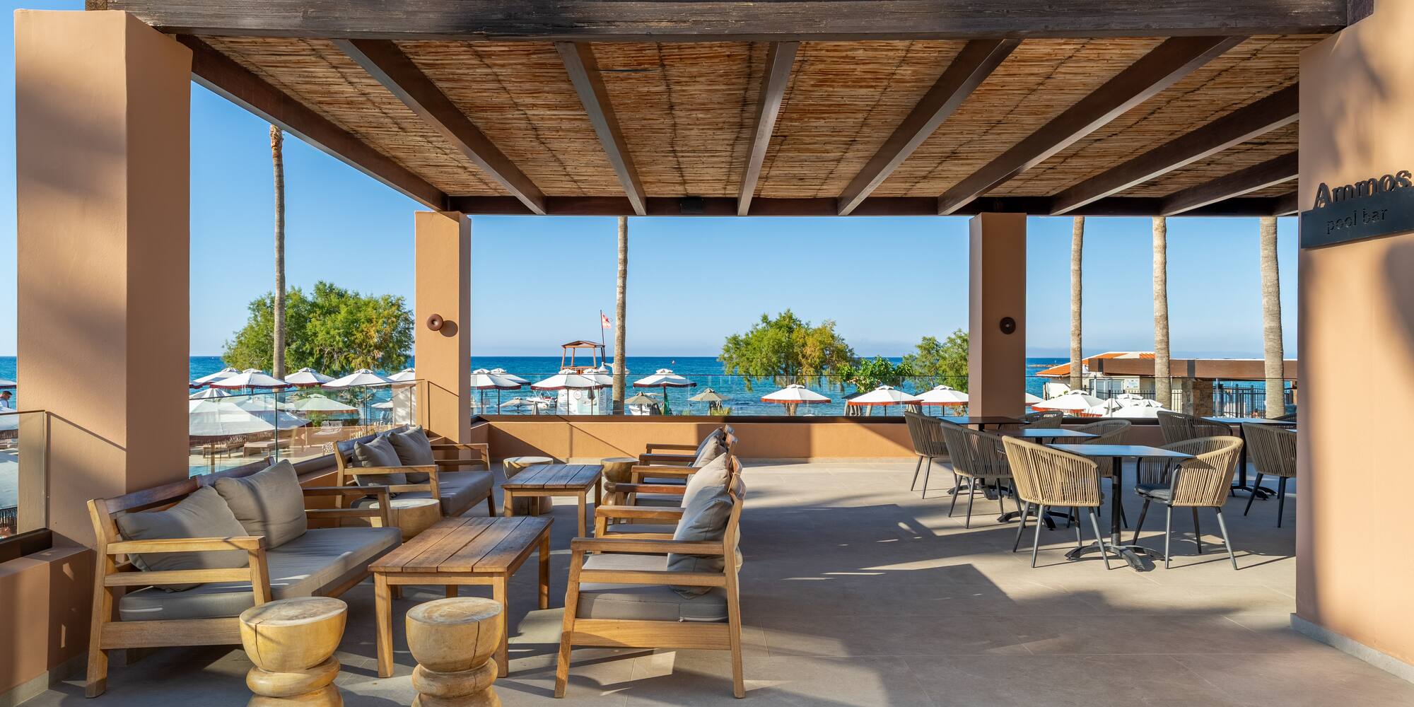 Ammos pool bar terrace with shaded lounge and dining, beach and sea view.