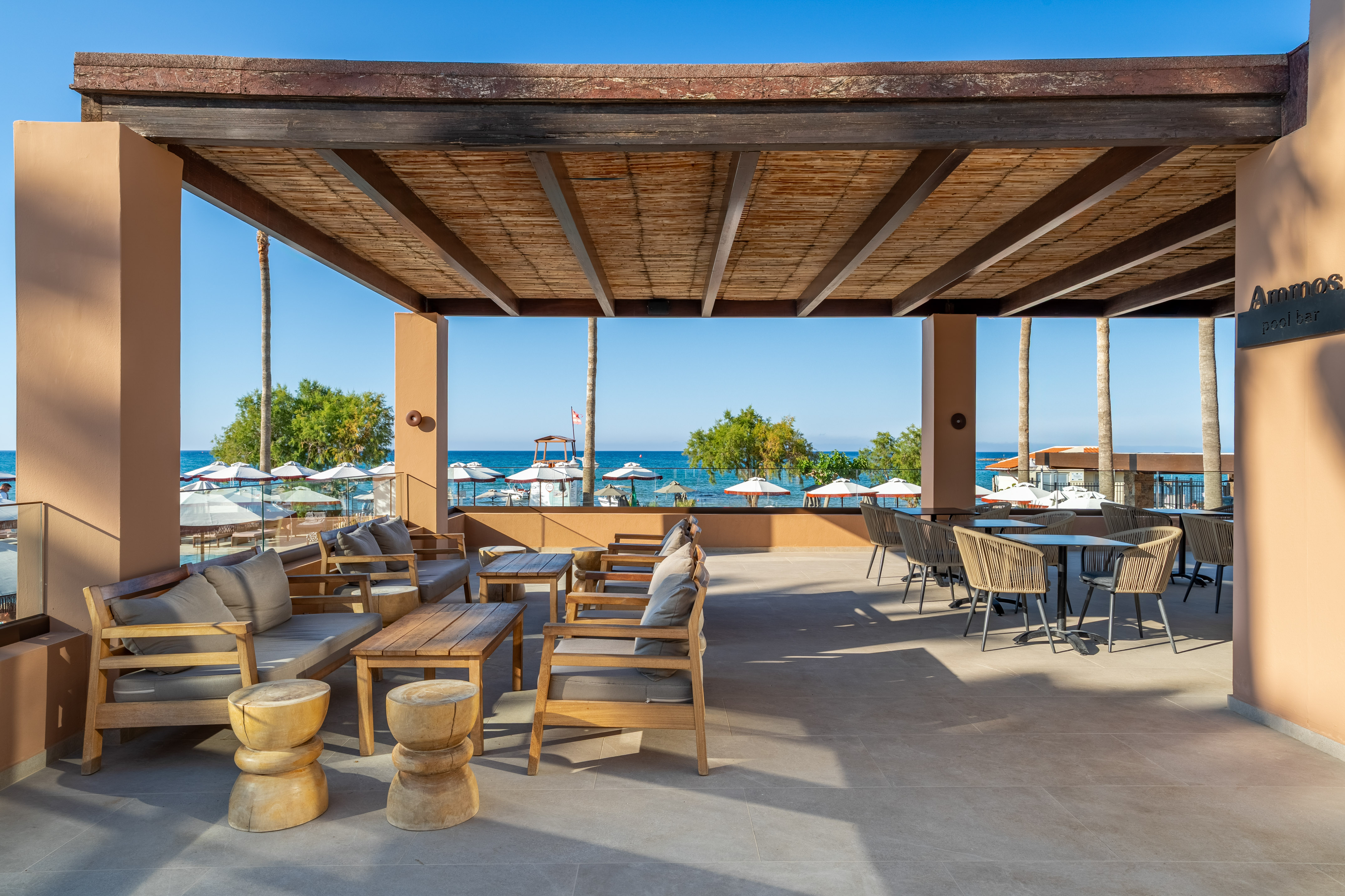 Ammos pool bar terrace with shaded lounge and dining, beach and sea view.