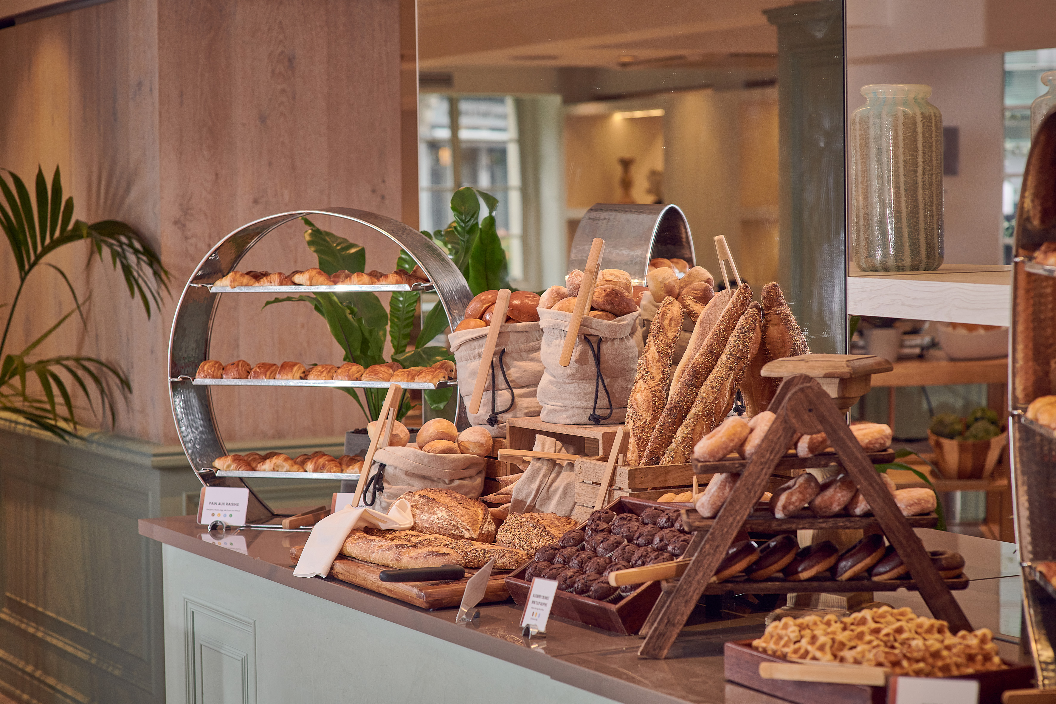 Hotel breakfast buffet with croissants, artisanal bread, rolls, and pastries.