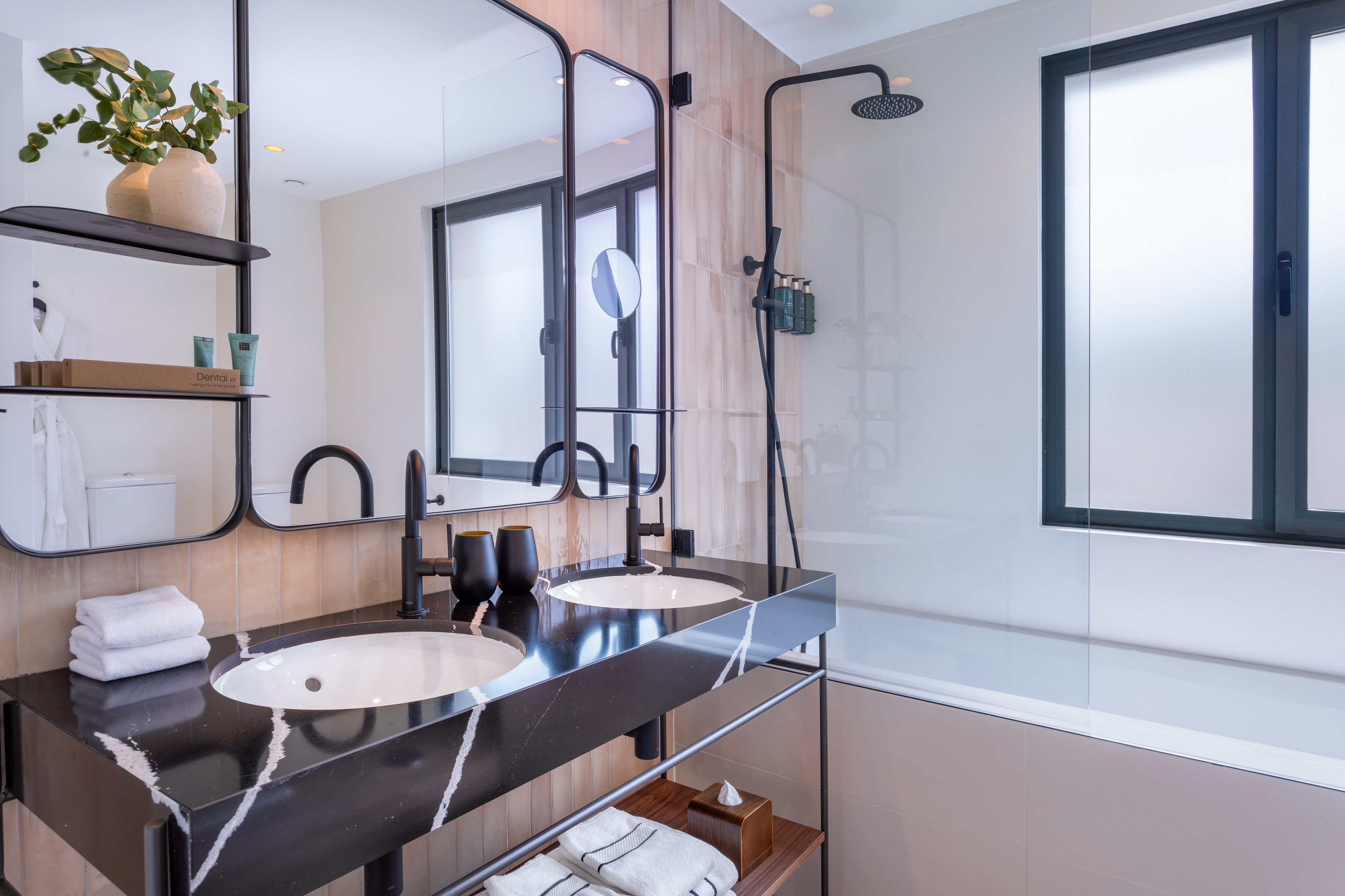 Modern bathroom design with black marble double vanity and rainfall shower.