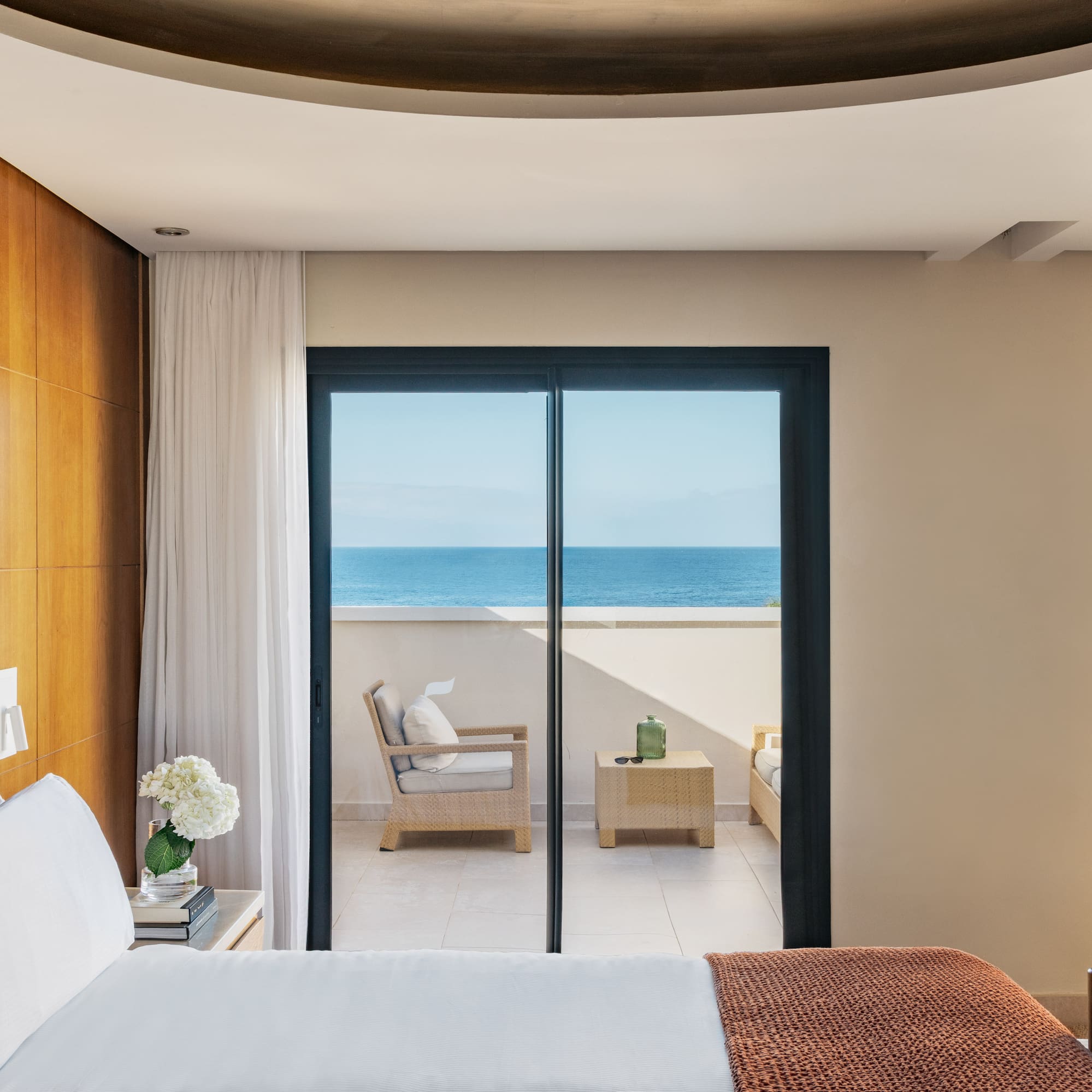 a bedroom with a glass door leading to the ocean