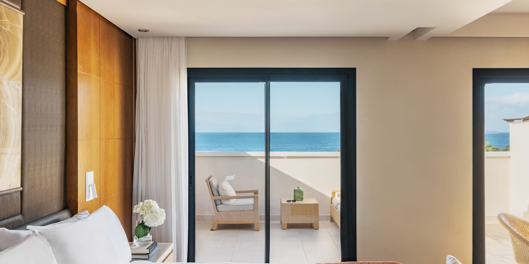 a bedroom with a glass door leading to the ocean